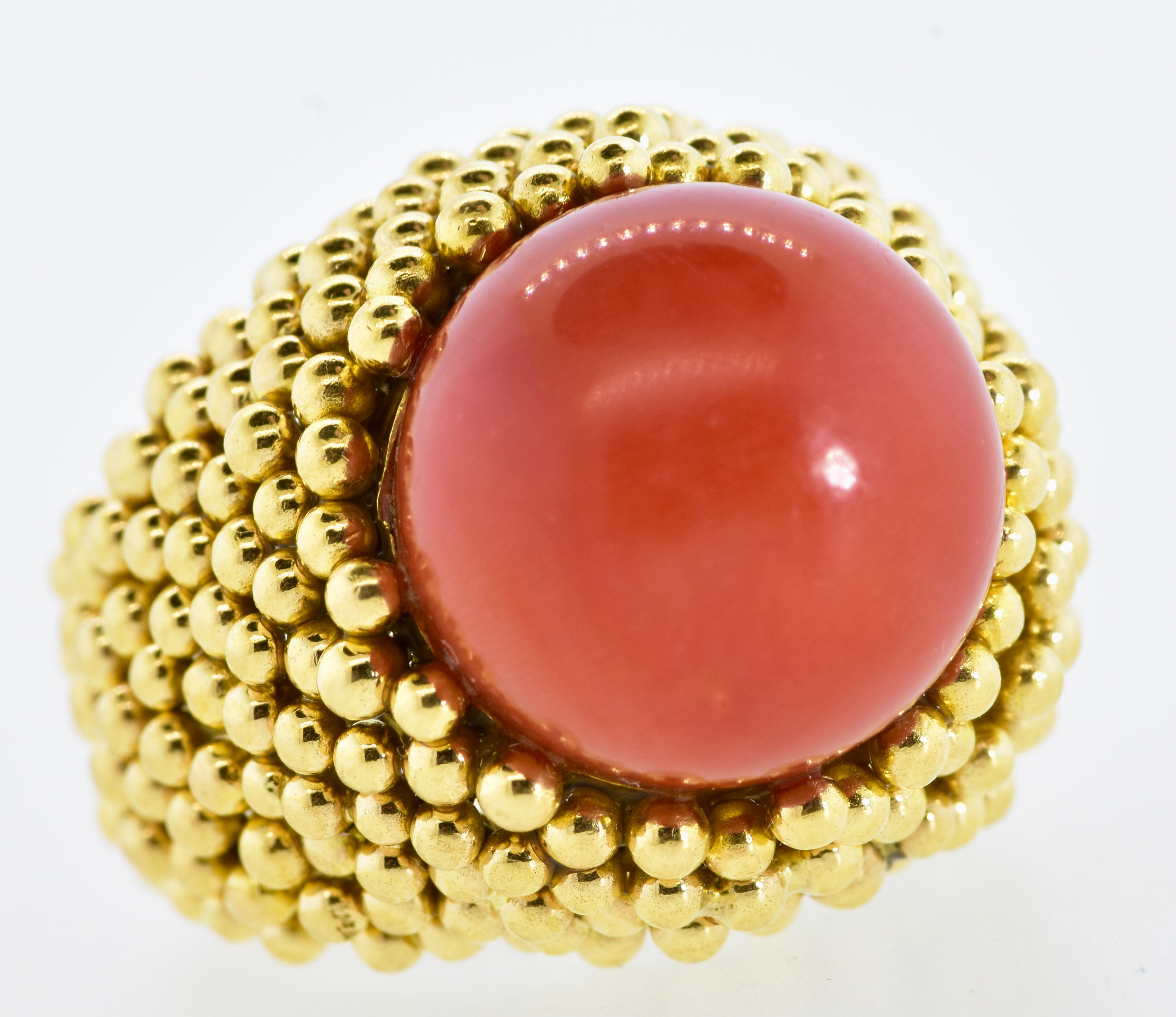 18K vintage ring centering a deep orange (oxblood) natural coral bead measuring 15.5 in diameter. The coral is natural and even in color.  Underneath the stone, there is a slight color change This hand made ring is studded with yellow gold balls