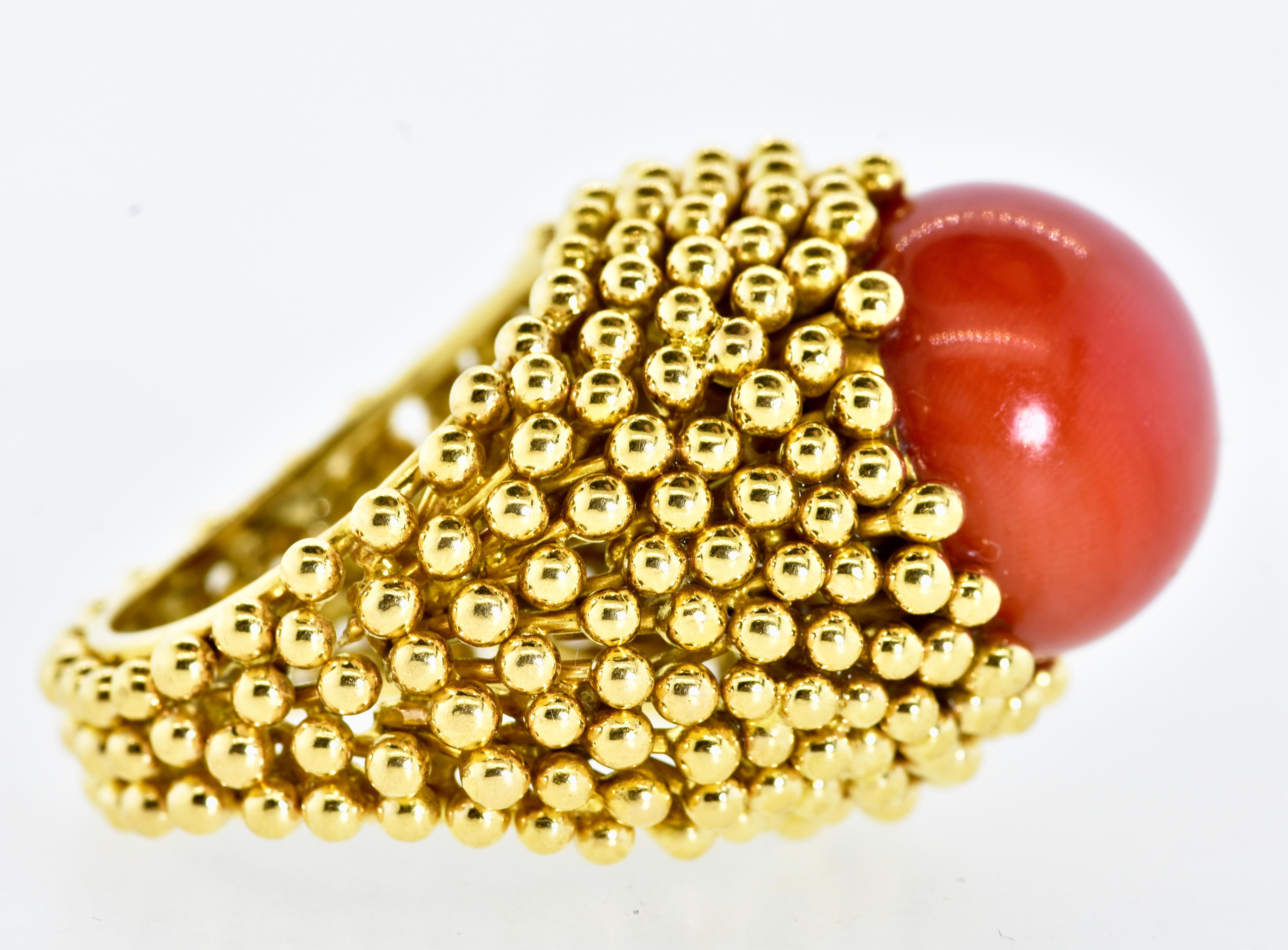 18K yellow gold large and bold ring centering a deep red/orange (oxblood) natural coral bead measuring 15.5 in diameter. The coral is  even in color. Underneath the stone, there is a slight color change typical of natural coral.  

 This hand made