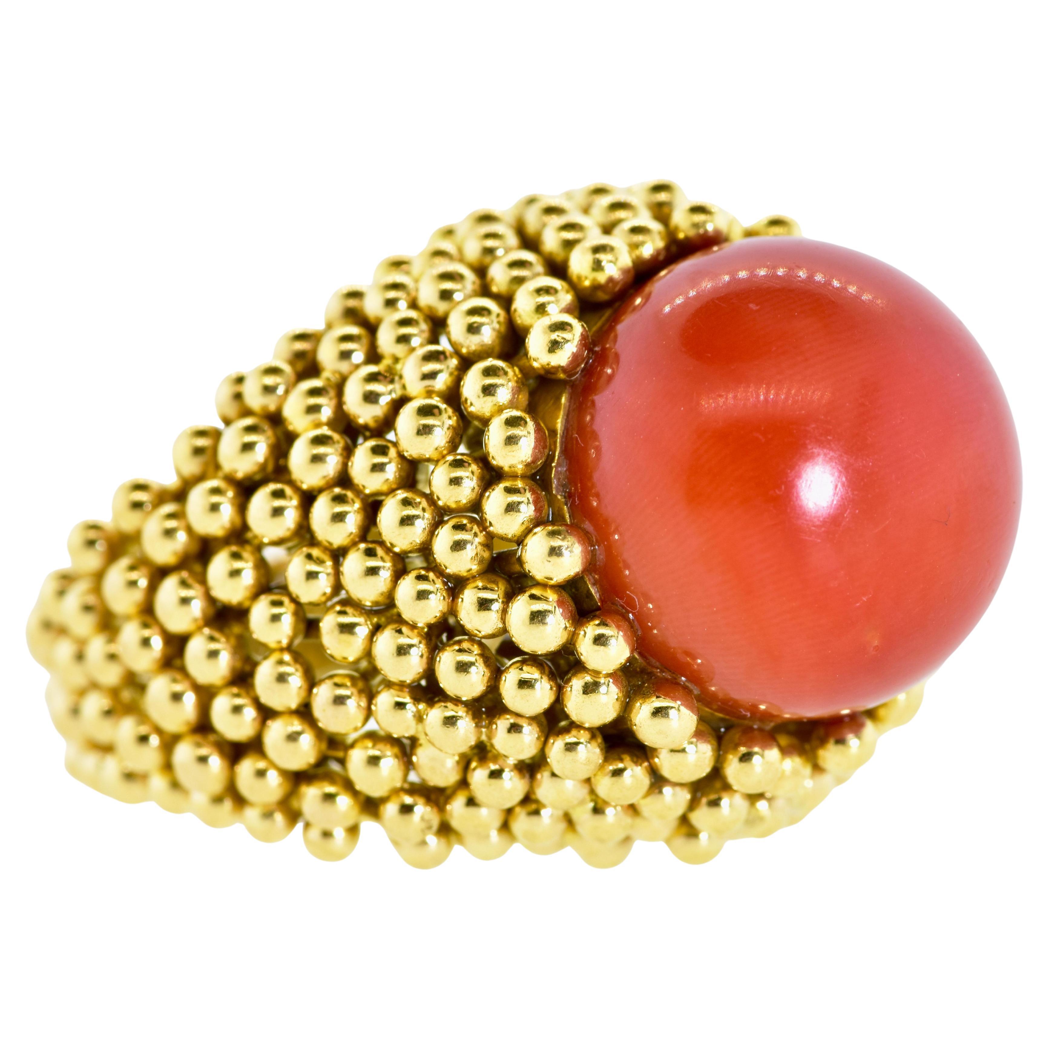 Anello in oro giallo 18 carati, grande e audace, con al centro una perla di corallo naturale rosso/arancio intenso (sangue di bue) di 15,5 di diametro. Il colore del corallo è uniforme. Sotto la pietra c'è un leggero cambiamento di colore tipico del