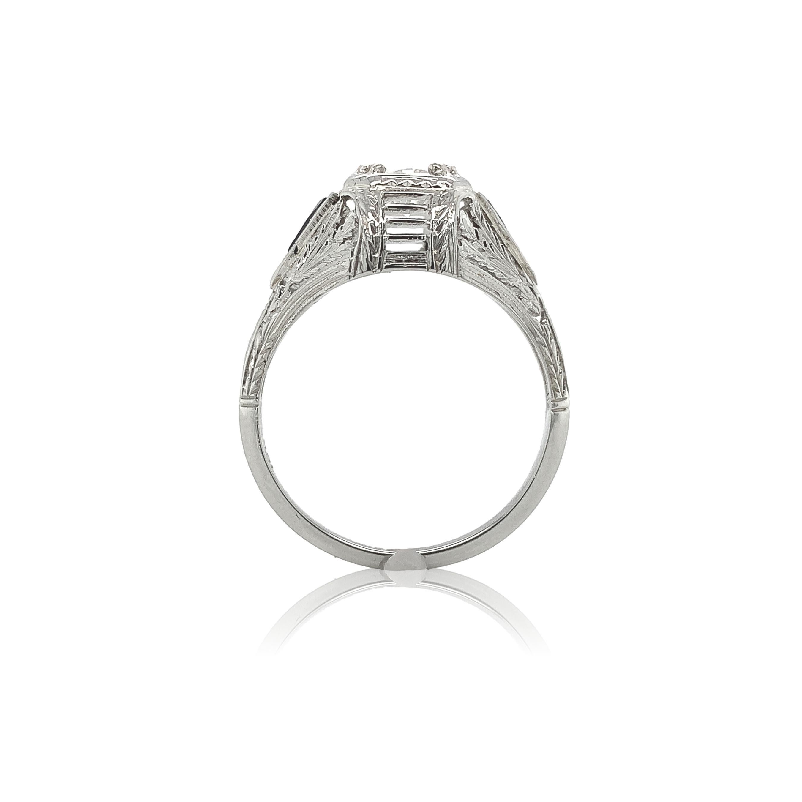 Art Deco 18K white gold filigree .41ct diamond ring. The GIA report #2231041985 states circular brilliant cut natural diamond measuring 4.78mm x 4.94mm x 2.79mm with G color and VS2 clarity.  There are 2 triangular French cut synthetic blue sapphire