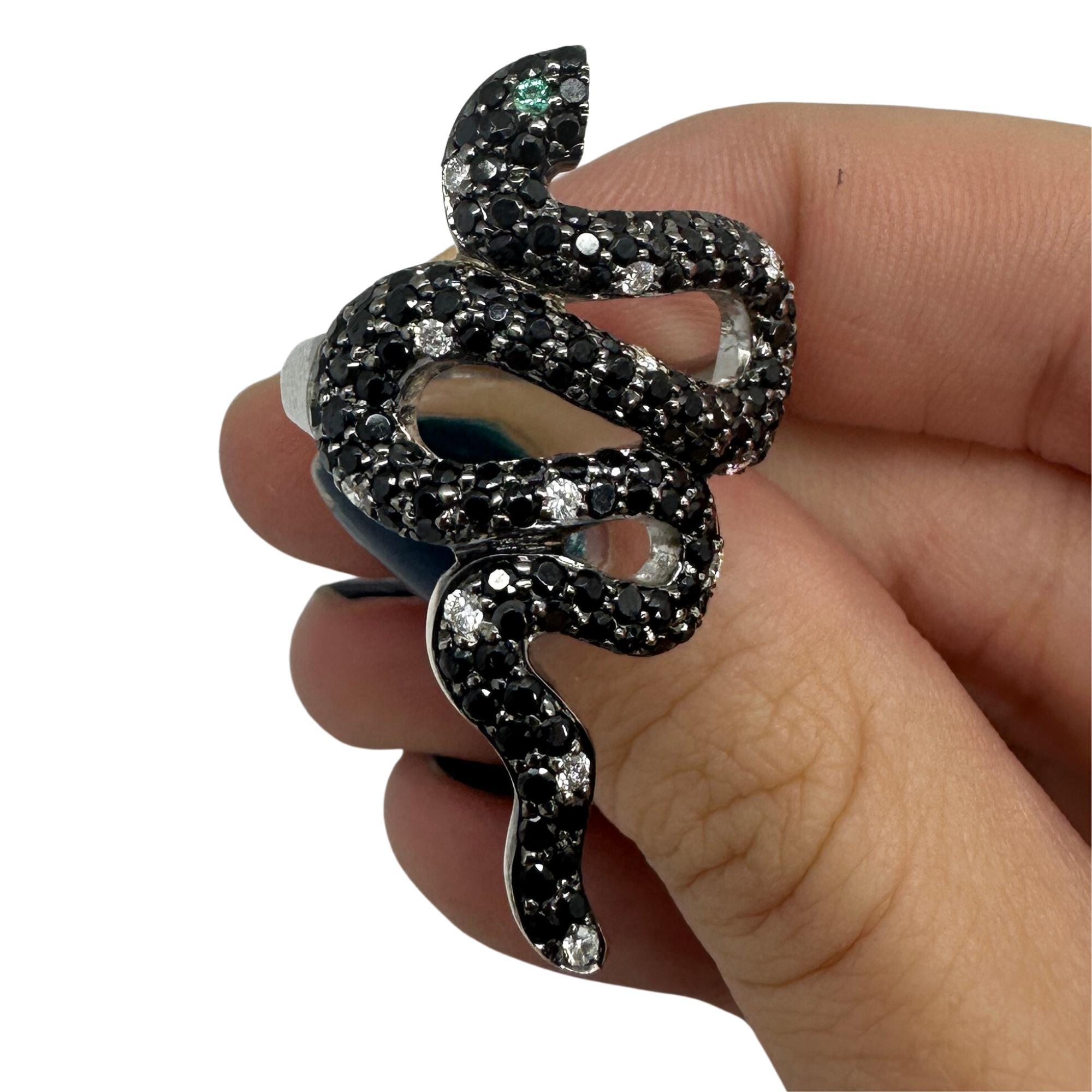 Showcasing our 18K Black and White Diamond and Emerald Snake Ring. Crafted in 18k White Gold, this unique ring features 2.18 carats of Black Diamonds, 0.15 carats of White Diamonds, and 0.10 carats of Emerald, all set in a bold snake design. 

18K