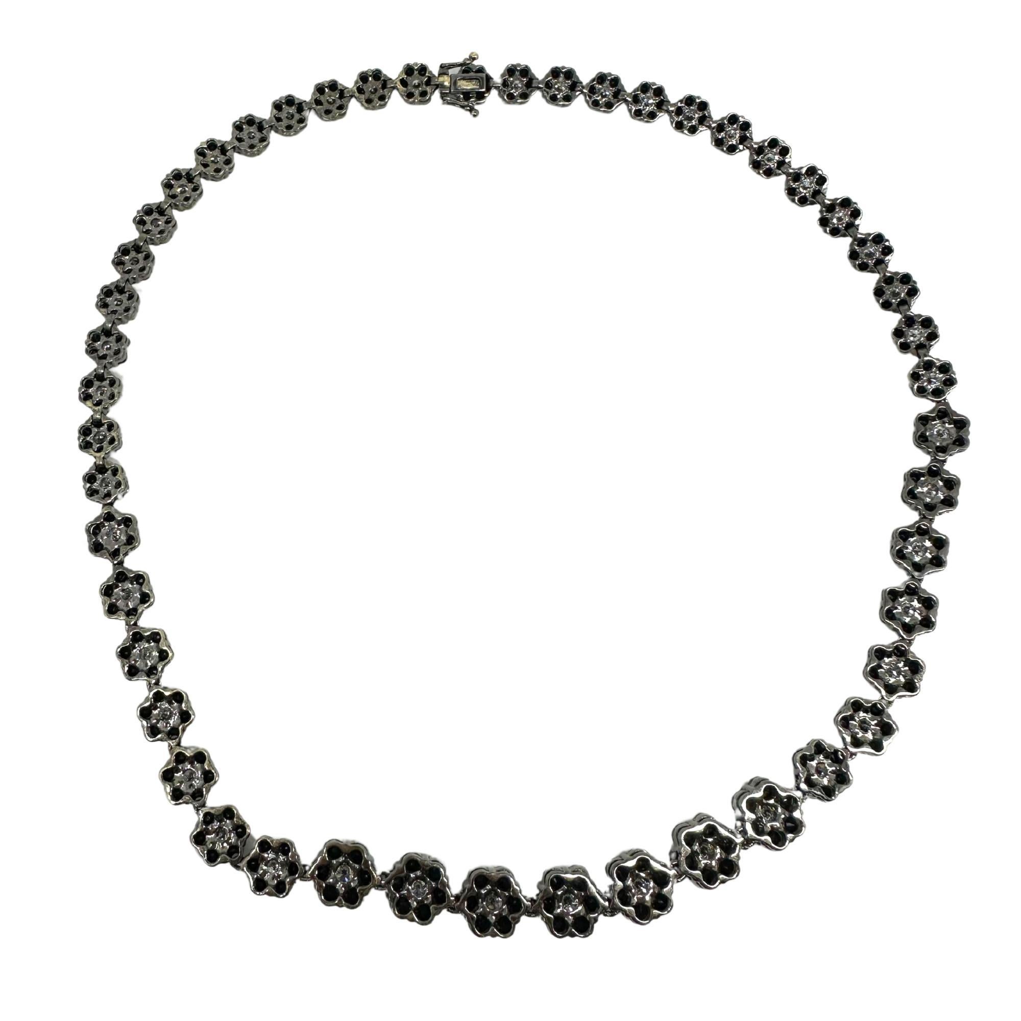 Diese elegante Halskette aus 18 Karat Gold besticht durch ihr florales Design, das mit einer beeindruckenden Reihe schwarzer und weißer Diamanten besetzt ist. Insgesamt 32,22 Karat schwarze Diamanten sorgen für einen starken Kontrast, während 5,96
