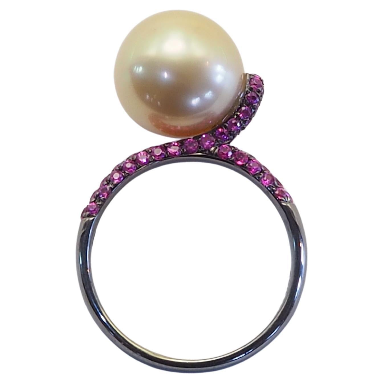 Eleva tu colección con este exquisito anillo de oro rodiado negro de 18 quilates con una luminosa perla dorada del Mar del Sur de 11 mm, célebre por su rico tono natural y su brillo excepcional. Flanqueada por 0,62 quilates de vibrantes zafiros