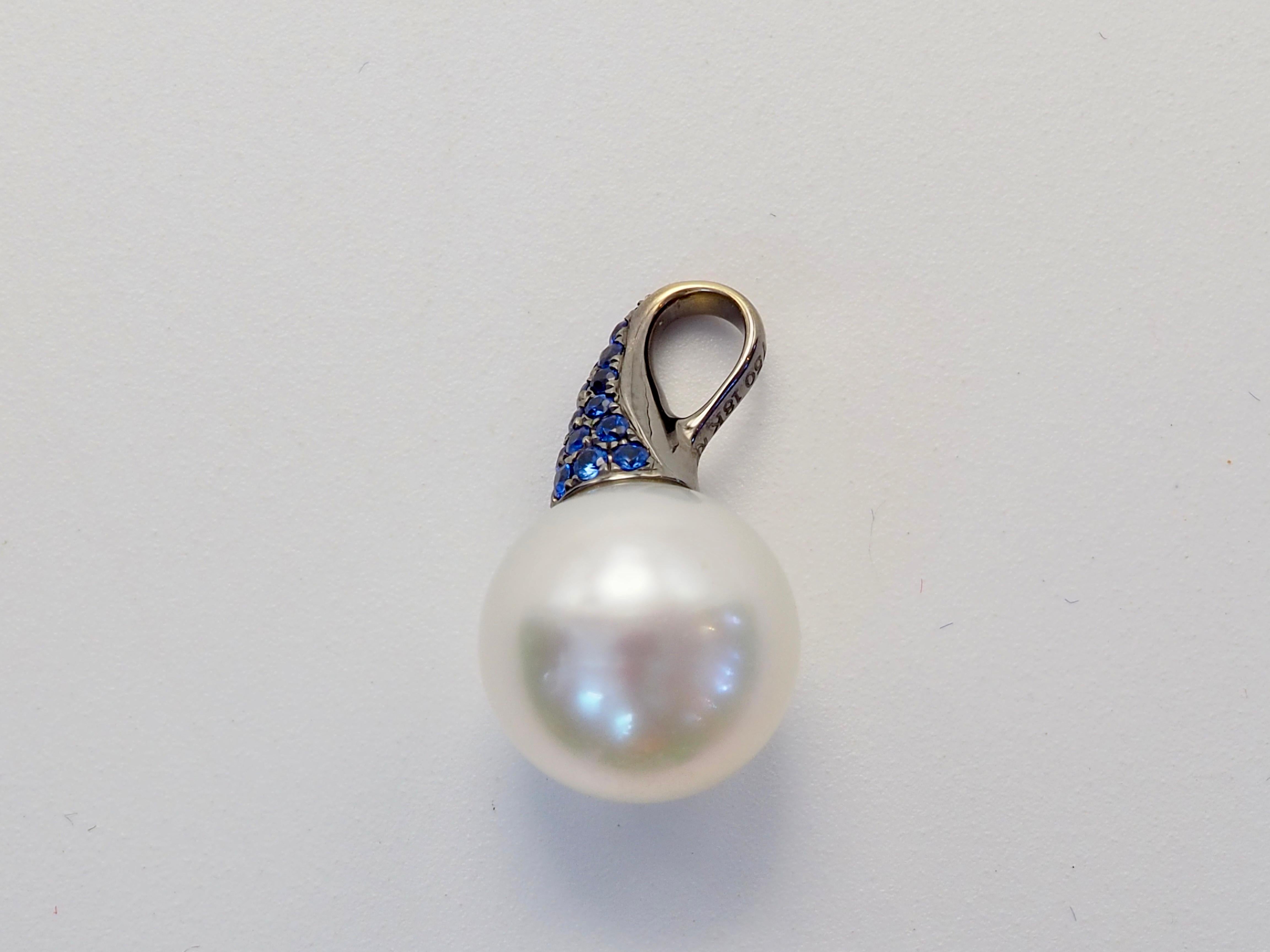 Marvelous artwork. The South Sea Pearl is white and perfectly round with little blemishes present and the cluster of blue sapphire is made up of top color which shines brightly. The curvature of metalwork hints of aquatic motif and very unique. The