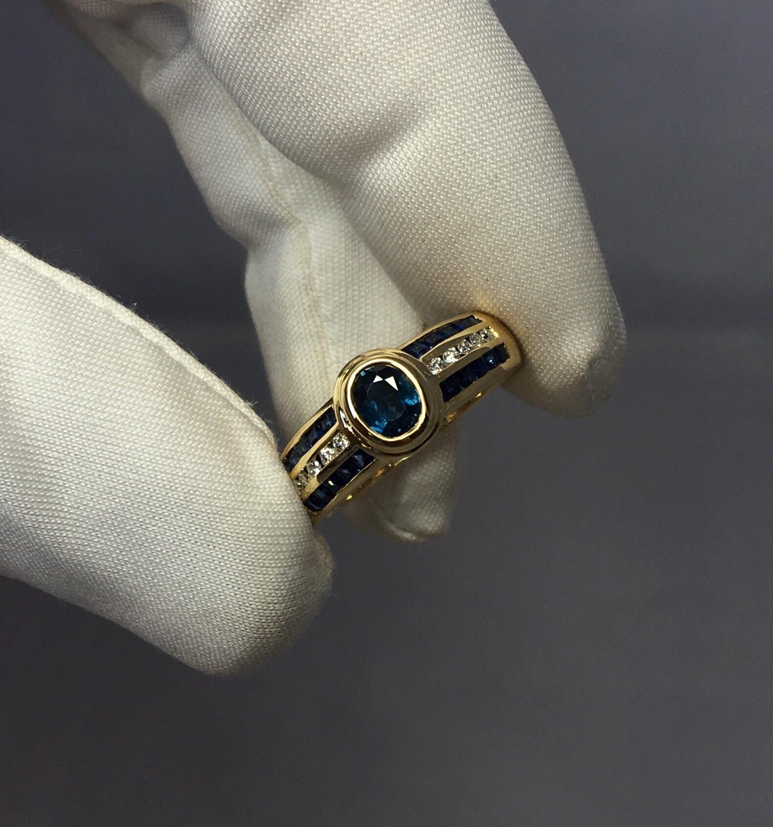 Stunning oval cut blue sapphire ring with round diamond and square sapphire accents.
All set in a fine 18k yellow gold European made ring. European hallmarks, either Dutch or Belgian.

The centre sapphire is approx 0.80 carat with a beautiful blue