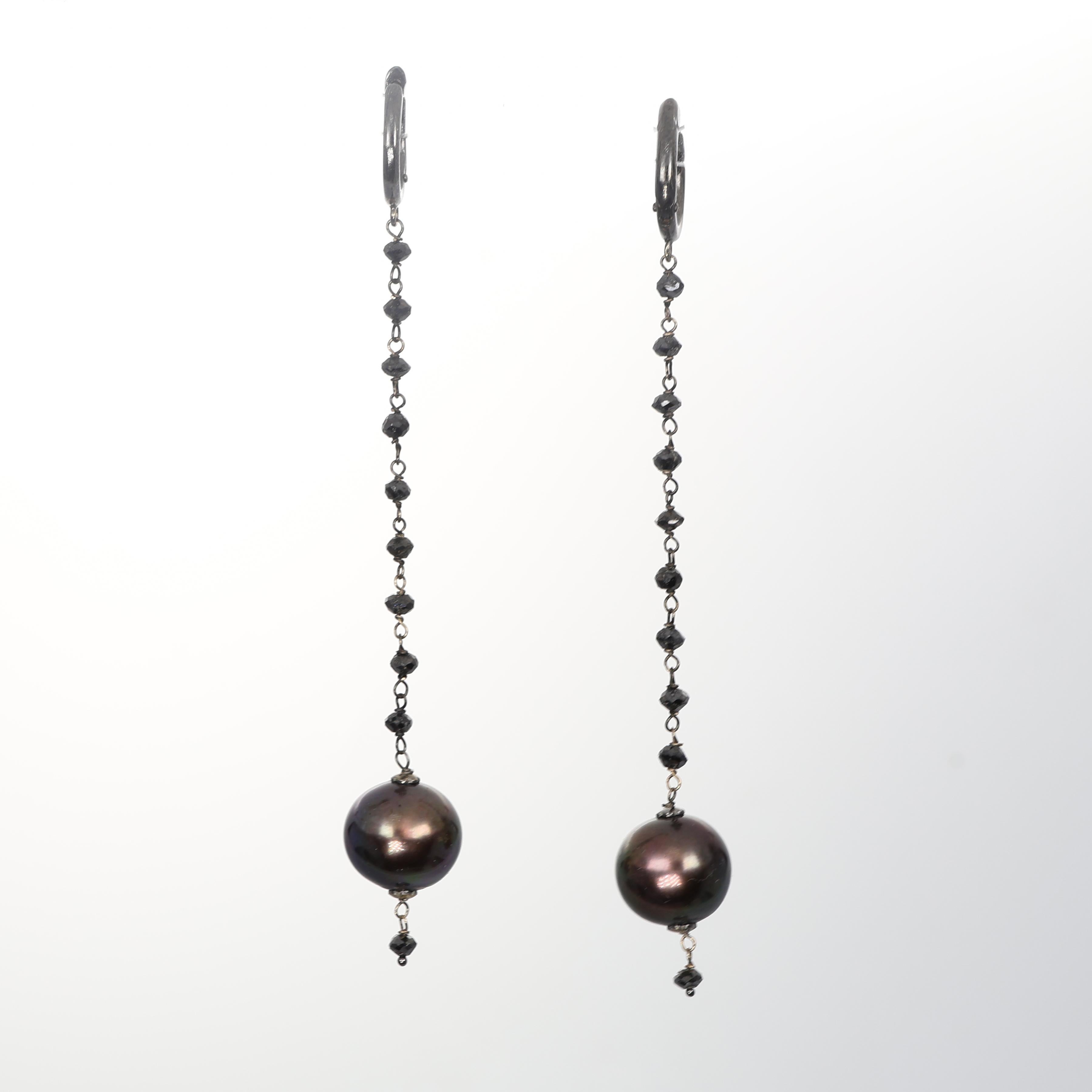 A refined expression of contrast and sophistication, these drop earrings in burnished 18K white gold feature a delicate chain of black diamonds leading to an elegant dark pearl. The interplay of deep hues and shimmering facets creates a strikingly