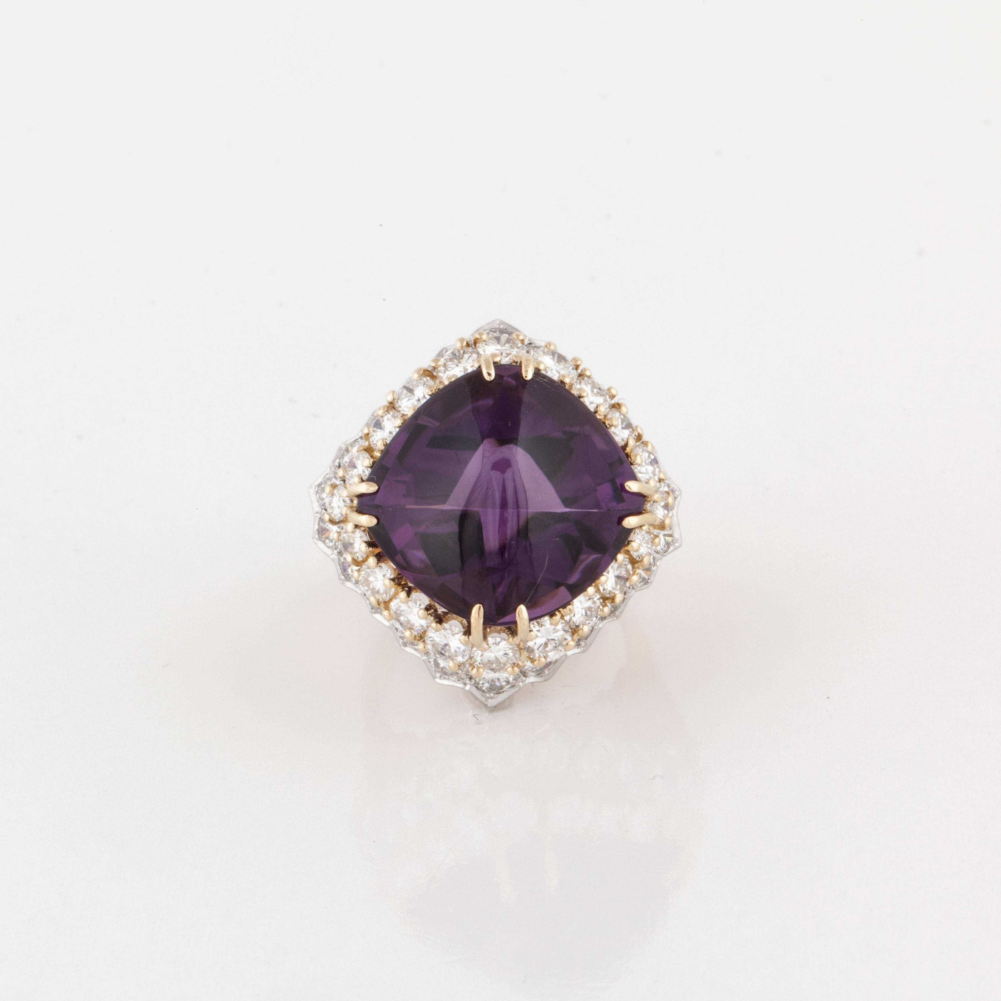 18K yellow and white gold ring featuring a cabochon amethyst with faceting on the bottom in the center.  The amethyst is framed by two layers of round diamonds.  One layer of diamonds are set in yellow gold and the bottom layer is set in white gold.