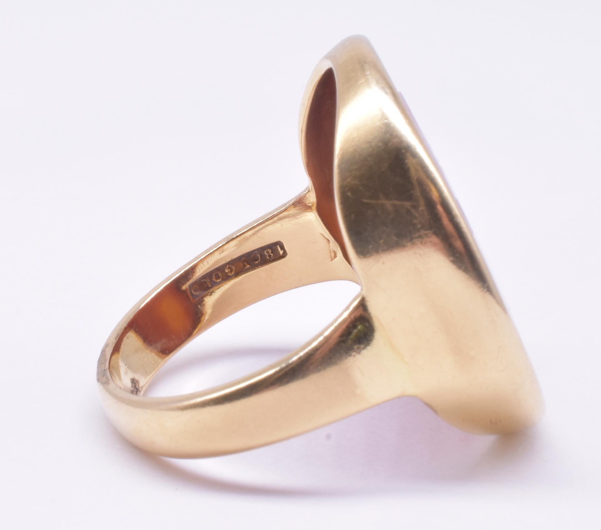 This is a big, bold signet ring with a Carnelian base and a band of 18K, the phrase 