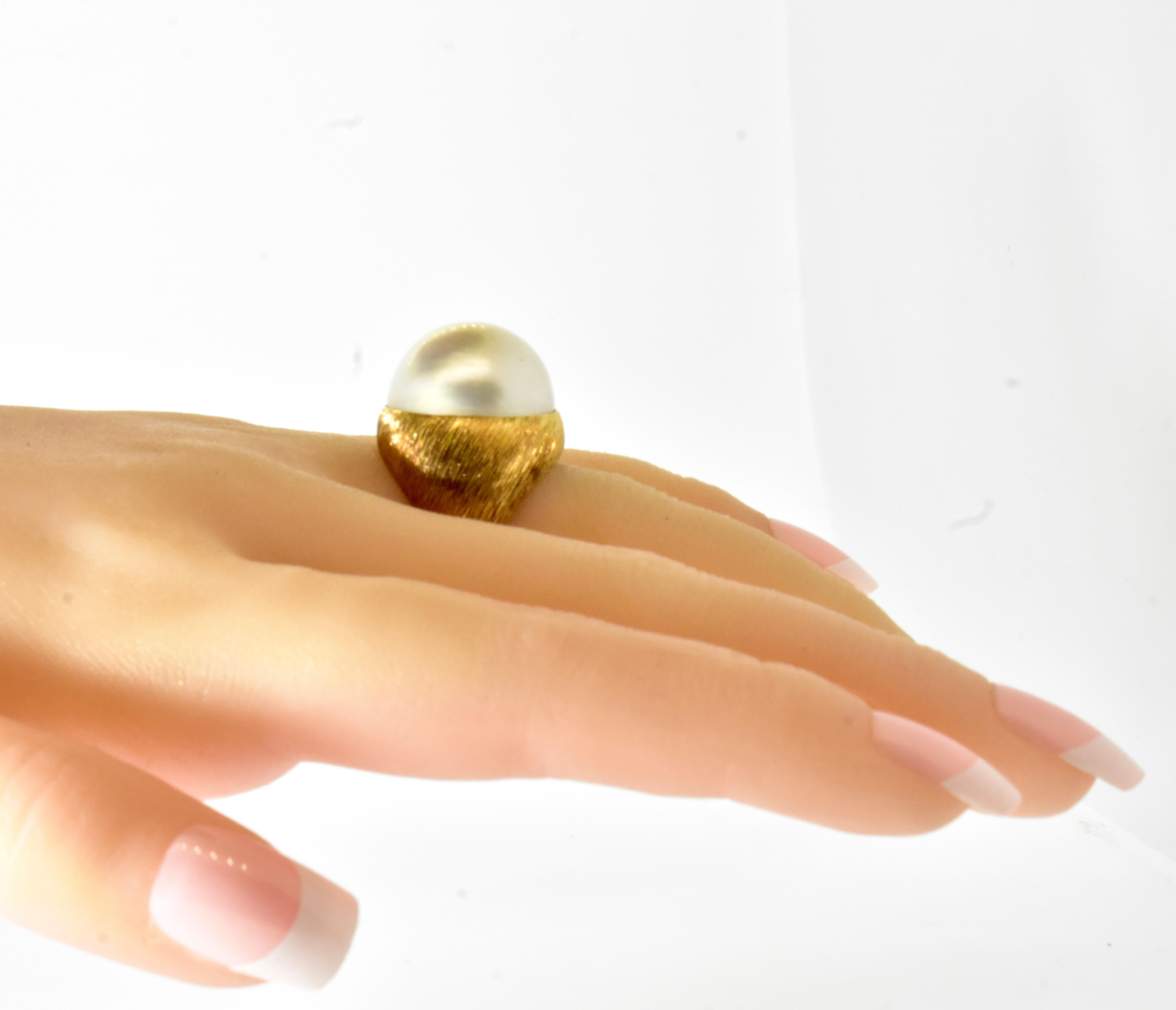 18K yellow gold etched in a swirl like motif centering a very fine and very large mobe pearl measuring 19.4 mm.  The mobe pearl is very fine with wonderful luminescence and a clean surface.

  This is a vintage ring from circa 1960.  It bears no