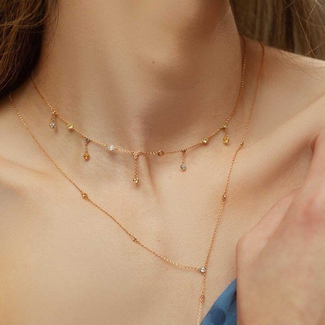 Questo vibrante girocollo in oro giallo 18 carati è ornato da una serie di brillanti gemme brasiliane, tra cui Citrino, Peridoto, Topazio blu, Ametista e Rosa rodolite. Le delicate gemme, di dimensioni comprese tra 1,5MM e 2,5MM, sono incastonate in