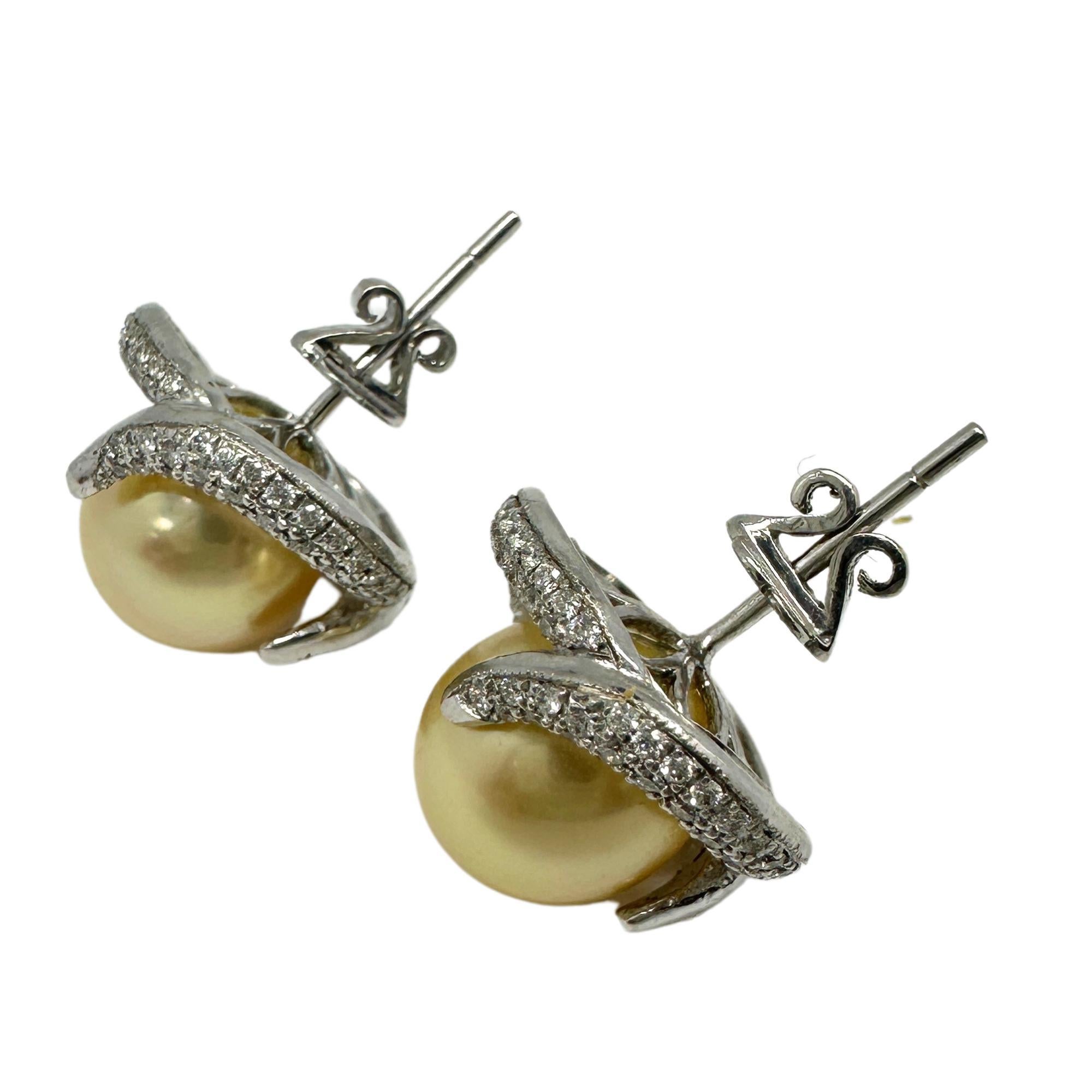 Eleva il tuo stile con questi splendidi orecchini con diamanti e perle in 18k. Realizzato in oro bianco 18 carati, ogni orecchino presenta una perla luminosa circondata da diamanti scintillanti per un totale di 0,97 carati. Con una misura di 0,60