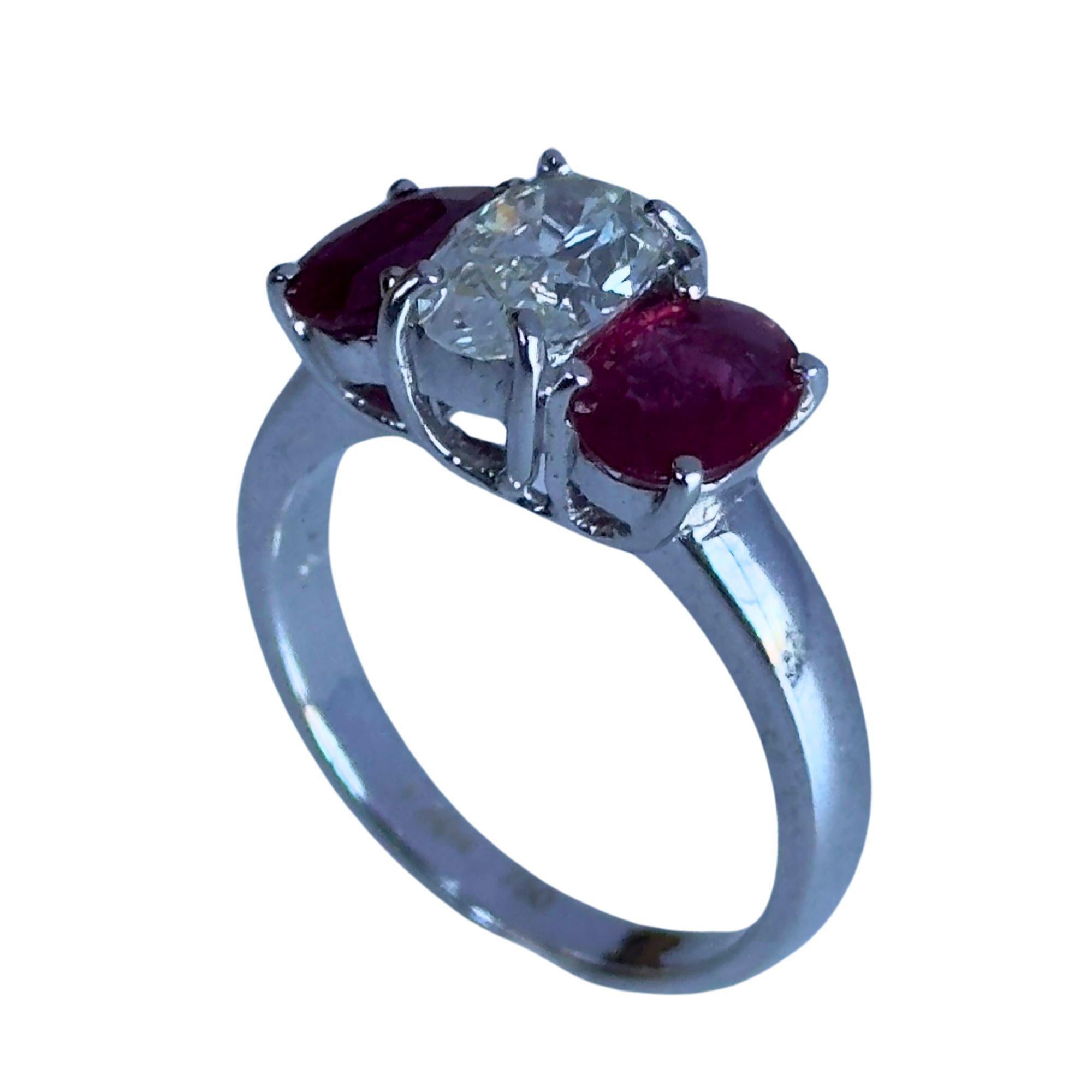 Add a pop of color to your jewelry collection with this 18k Diamond and Ruby Three Stone Ring. Crafted in 18k White Gold, this 5.7 gram ring features a diamond center weigh 1.02 carats with 2 rubies on each side weighing 1.58 carats all together.