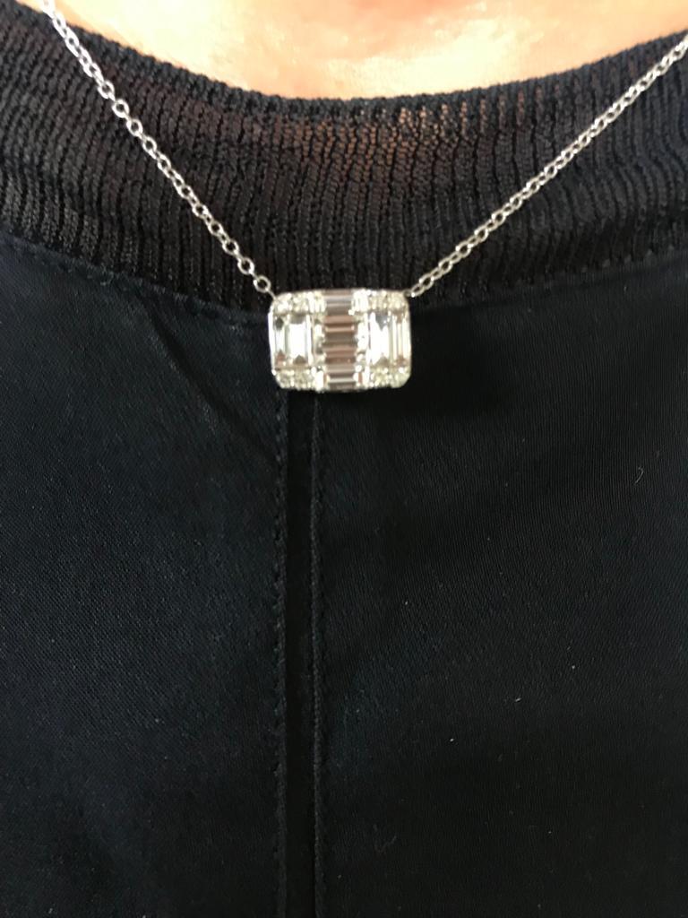 This stunning pendant on a chain is set in 18K white gold. The horizontal pendant consists of emerald, baguette, and round diamonds that create the look of a single emerald cut piece. The total carat weight is 1.72. The color of the diamonds are F,