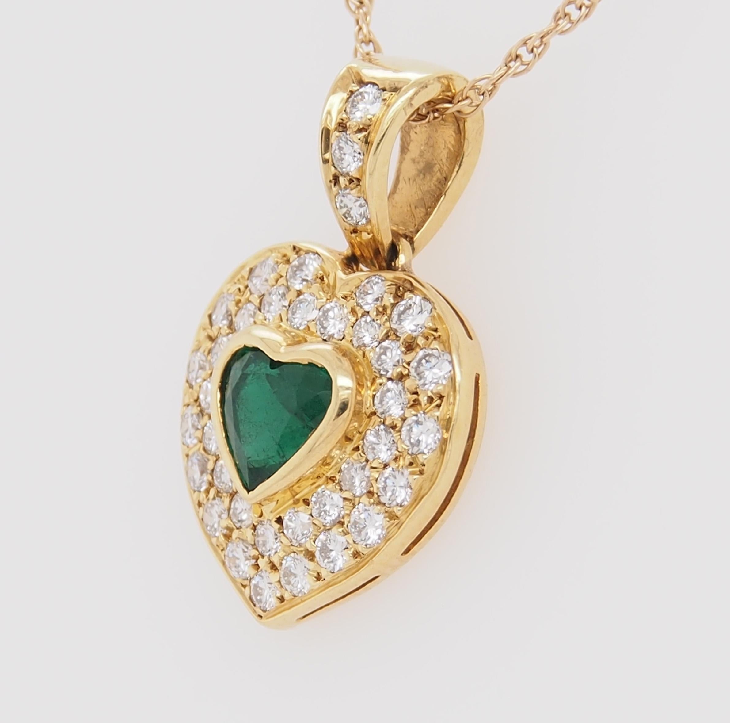 An 18K yellow gold heart shaped pendant. A heart shaped Emerald center approximately 1.05 ct is surrounded by (37) Round Brilliant Cut diamonds G-H in color, VS in clarity and 1.11 carat total weight. The pendant is 1 inch in height, approximately