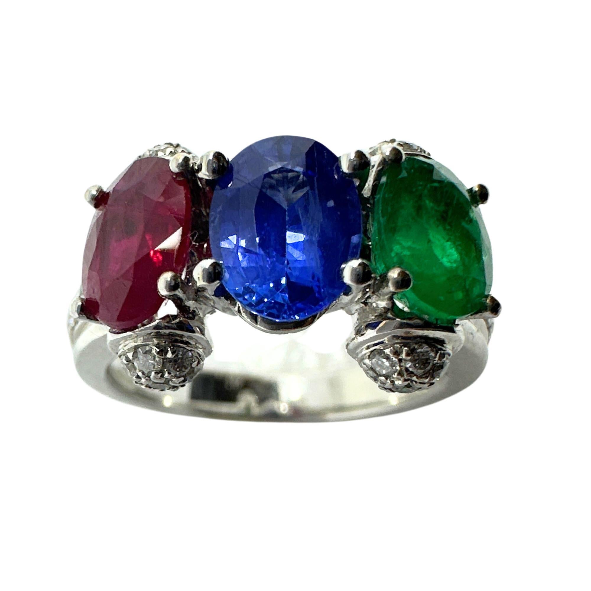 Erweitern Sie Ihre Sammlung mit unserem exquisiten 18k Gold Ring. Ein auffälliges Trio von Edelsteinen: Im Mittelpunkt steht ein leuchtend blauer Saphir, flankiert von einem sattroten Rubin und einem sattgrünen Smaragd. Das kühne Design wird durch