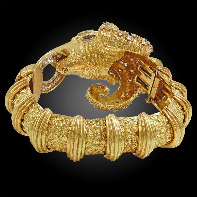 Designed as a rams head, this exquisite 18k yellow gold carved bangle is embellished with diamond accents throughout its head, and is further accentuated with sapphire eyes. This exceptional and bold statement piece dates back to the 1980s.