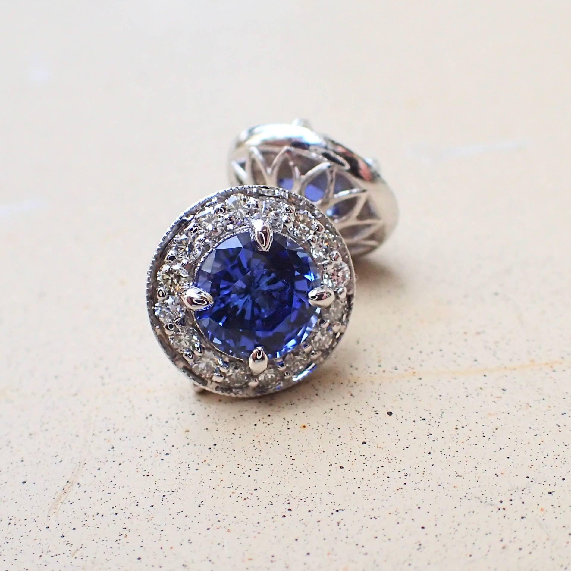 A pair of 18k white gold earrings are set with two (2) Round Brilliant Cut Chatham-Created Blue Sapphire that measure 6.0mm x 6.0mm and weigh a total of 2.21 carats with Clarity Grade VVS-VS and thirty-two (32) Round Brilliant Cut Diamonds that