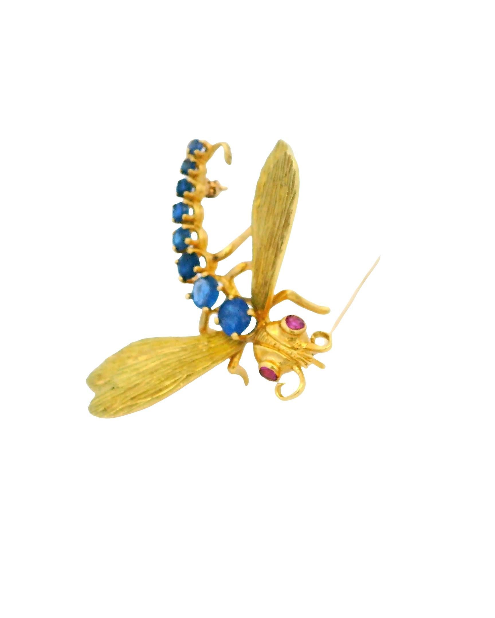 Fabricado en el siglo XXI, este exquisito broche presenta un llamativo diseño de un delicado insecto. El cuerpo está adornado con vibrantes zafiros azules, de un total de 1,0 quilate, complementados por vívidos rubíes rojos de 0,12 quilates. La