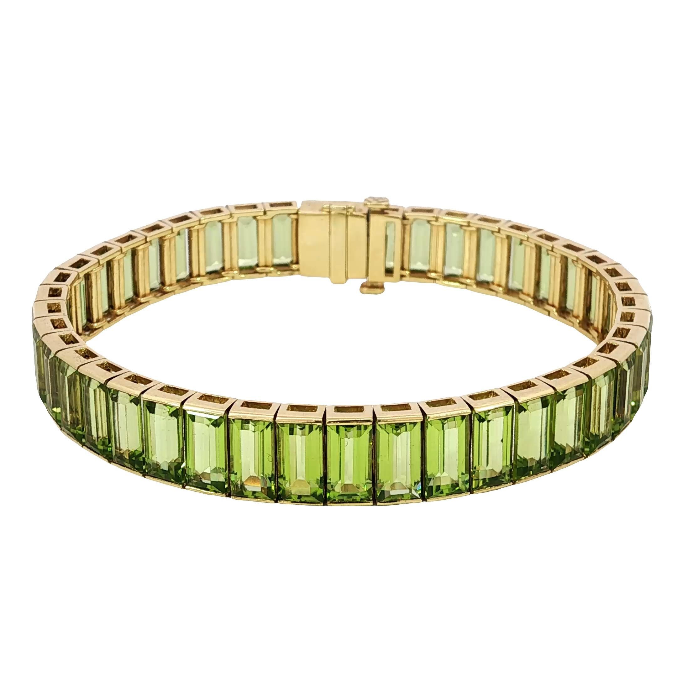 18K Emerald Cut Bracelet Peridot Straight Line Tennis Bracelet 18K Gold ~26ctw

This bracelet features an elegant line of emerald-cut peridot stones, each radiating a vivid green hue. Set in 18k yellow gold, the design enhances the natural color of