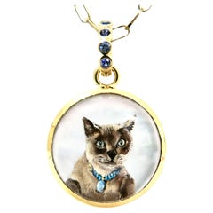 18k enhancer,  hand painted siamese cat, reverse crystal, blue sapphire bail.