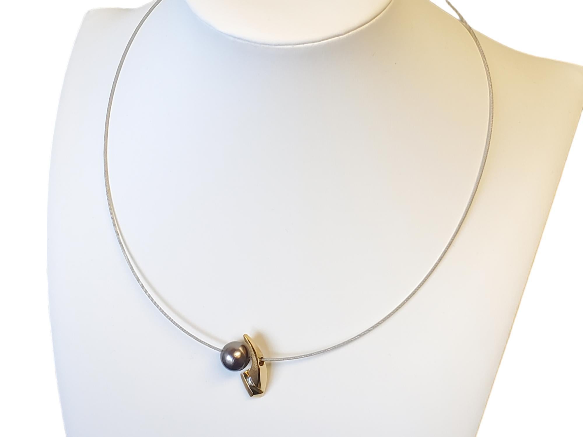 18k Designer Tahitian Pearl Diamond Steel Cable Necklace

Listed is a very chic modern 18k/steel cable necklace featuring an 18k pendant slide that shapes the side of this beautiful 10.7mm Tahitian Pearl. The diamond in the pendant is between