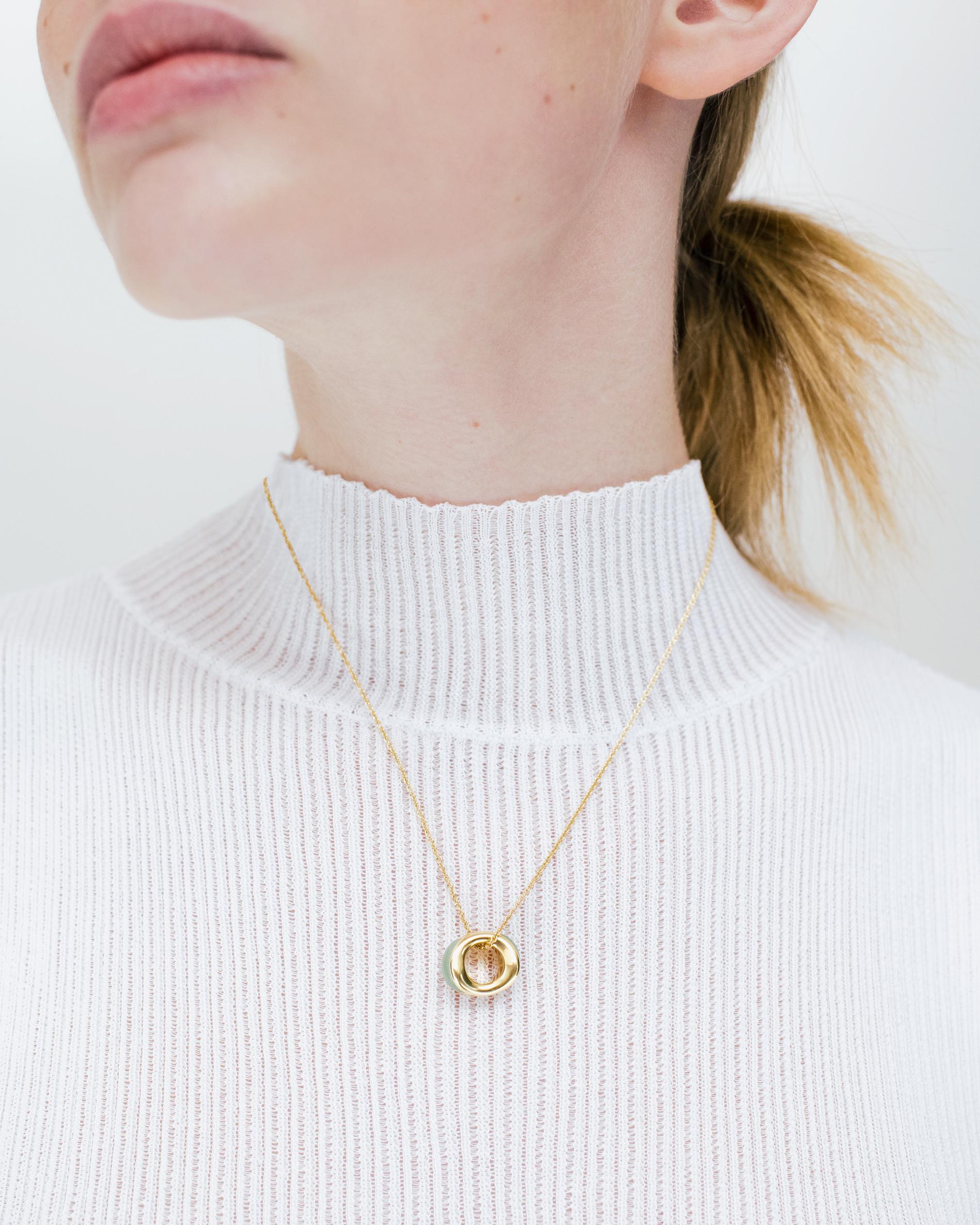 DILHAN Ciondolo etico in oro giallo e avventurina SU Wave Mini. Le linee organiche e il sottile equilibrio del ciondolo SU WAVE si ripetono qui con un effetto più tranquillo. Curve delicate e una pietra luminosa catturano il movimento della luce,