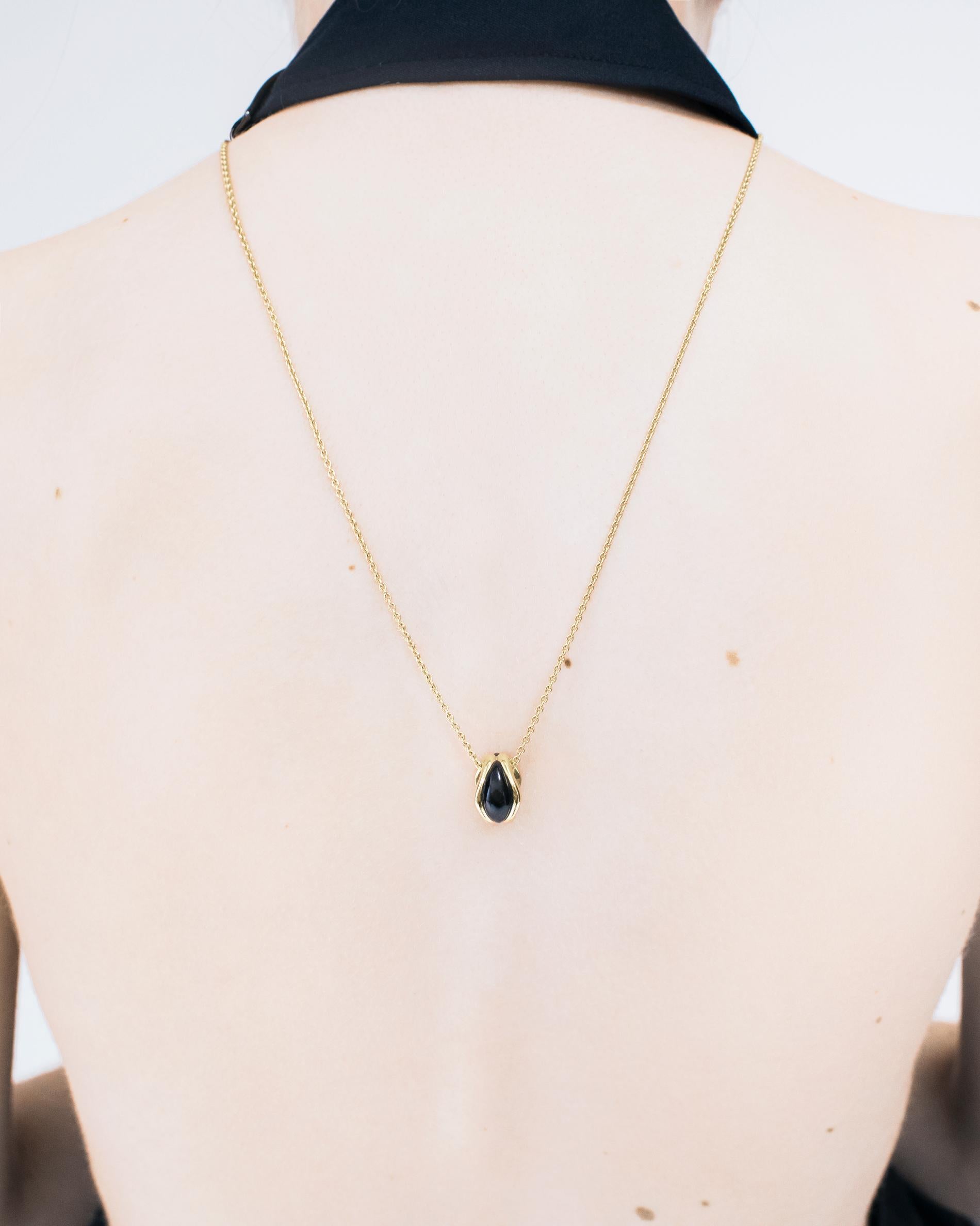 DILHAN Oro giallo etico 18k e onice lucidato. Questo ciondolo elegante e ben bilanciato presenta una pietra intagliata incastonata nell'oro increspato. Il suo design si ispira al movimento dell'acqua. La forma scultorea e il movimento fluido della