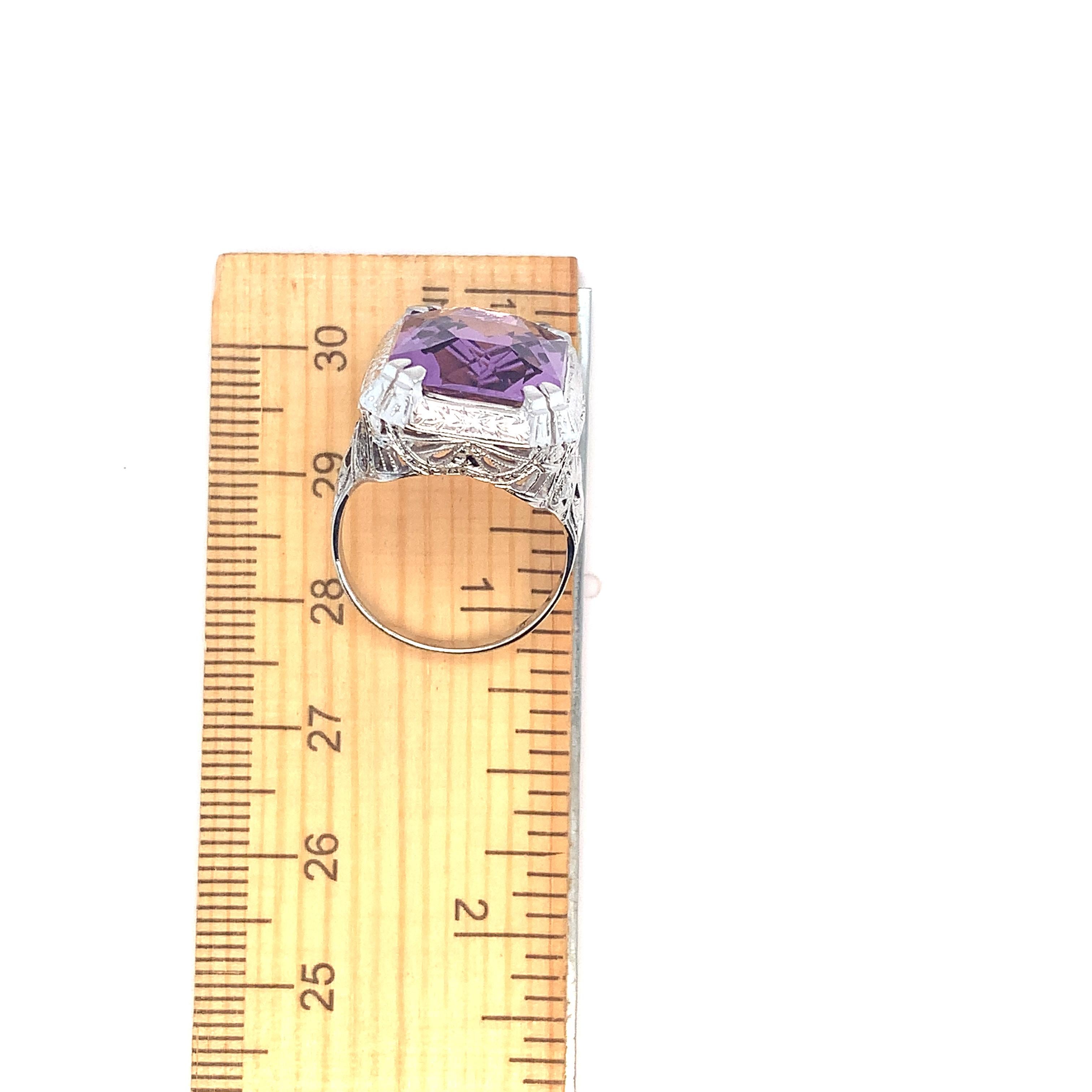18K white gold filigree Art Deco ring featuring a large amethyst weighing 9.09 carats. This is the original stone, carefully re-polished in the same rectangular brilliant cut. The amethyst measures about 16mm x 12mm. The ring fits a size 7 finger