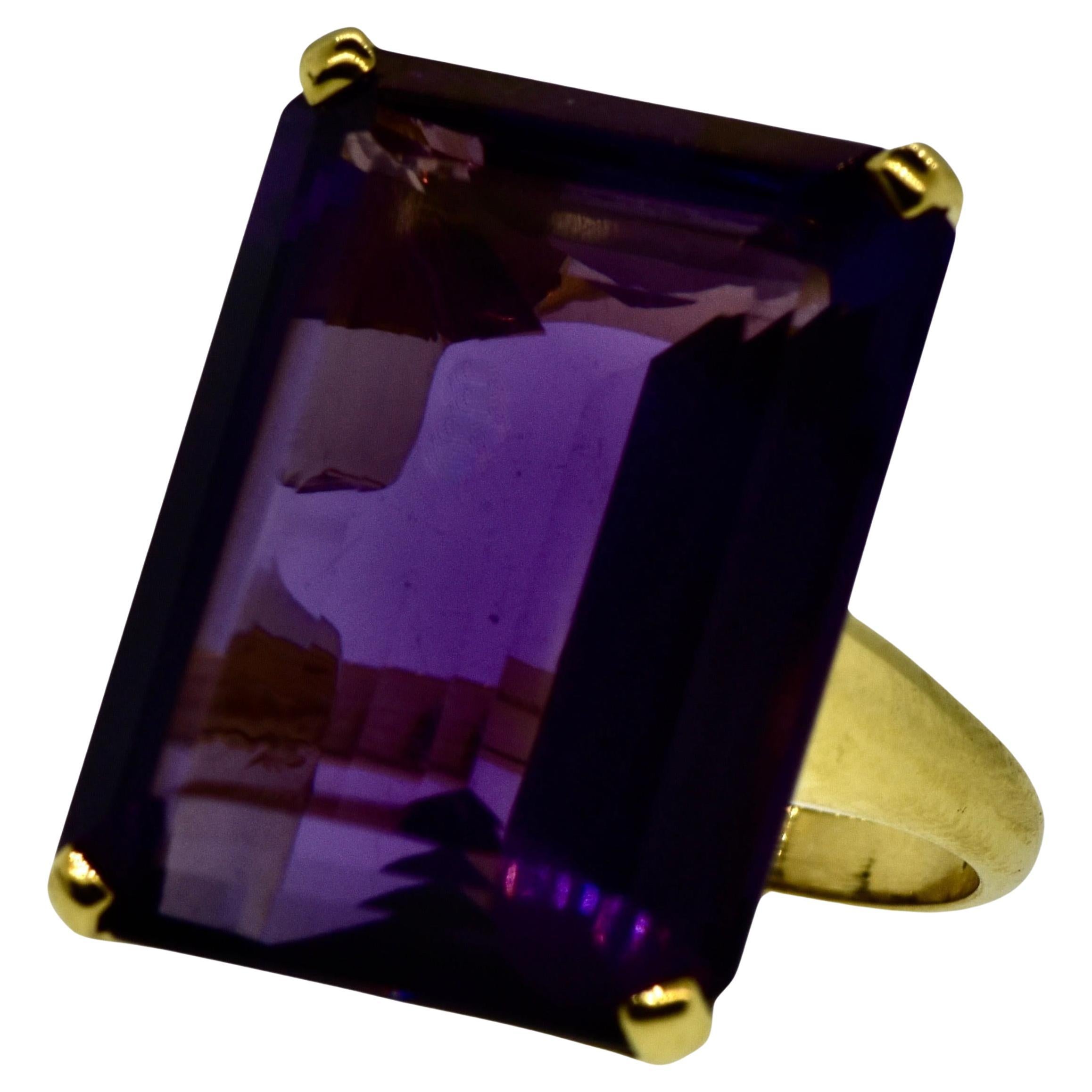Very fine large emerald cut amethyst displaying a vivid deep purple with flashes of red, this new ring is hand crafted in 18K yellow gold by Pierre/Famille of Aspen, CO. 

The long emerald cut amethyst weighs 36.21 cts. It is a size 6.5 and can be