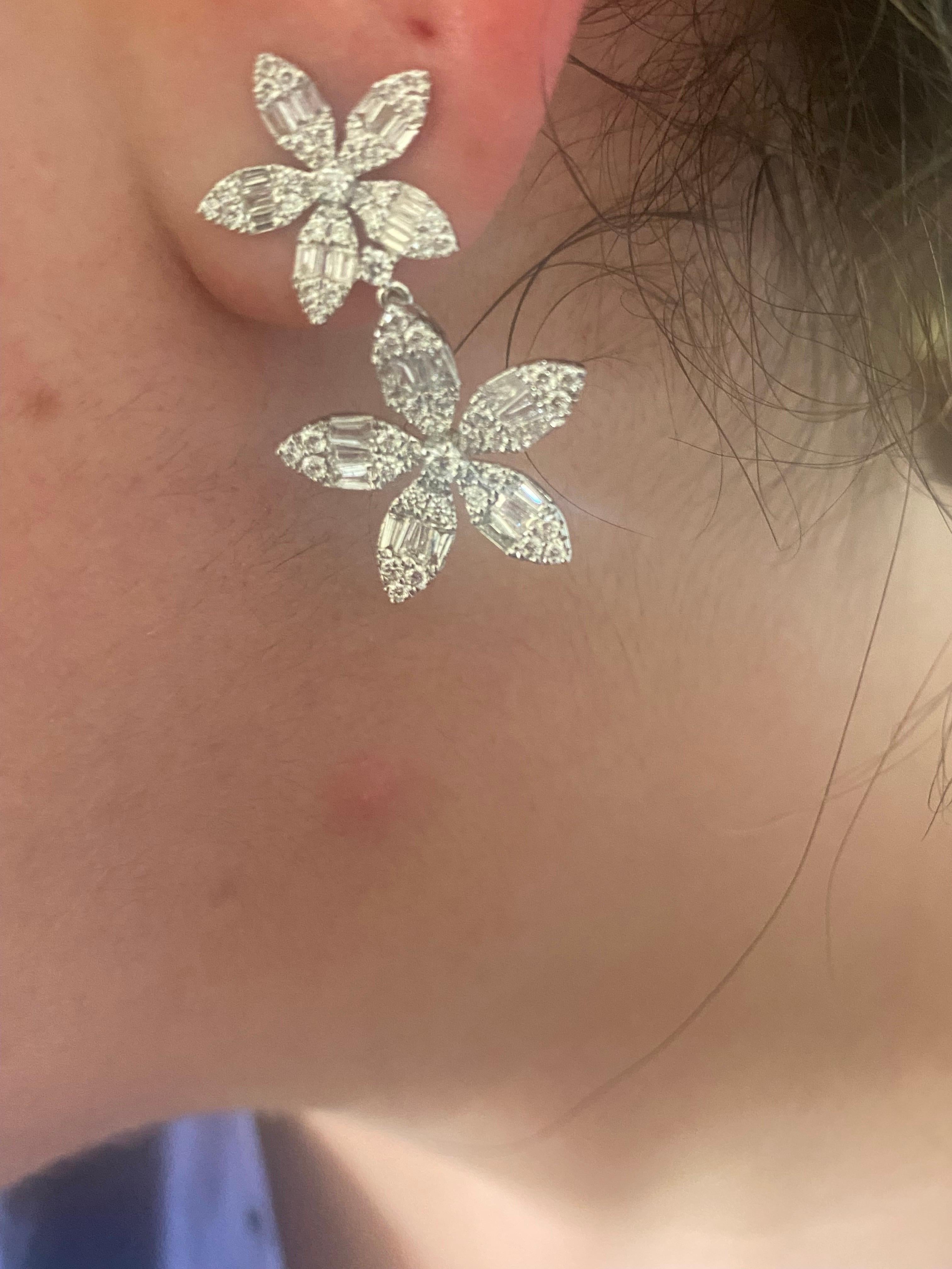 Diamond drop hanging earrings set in 18K white gold. The earrings are set with baguette and round diamonds in a double flower daisy style. The total diamond weight is 2.20 carats. The color of the stones are F, the clarity is VS1.