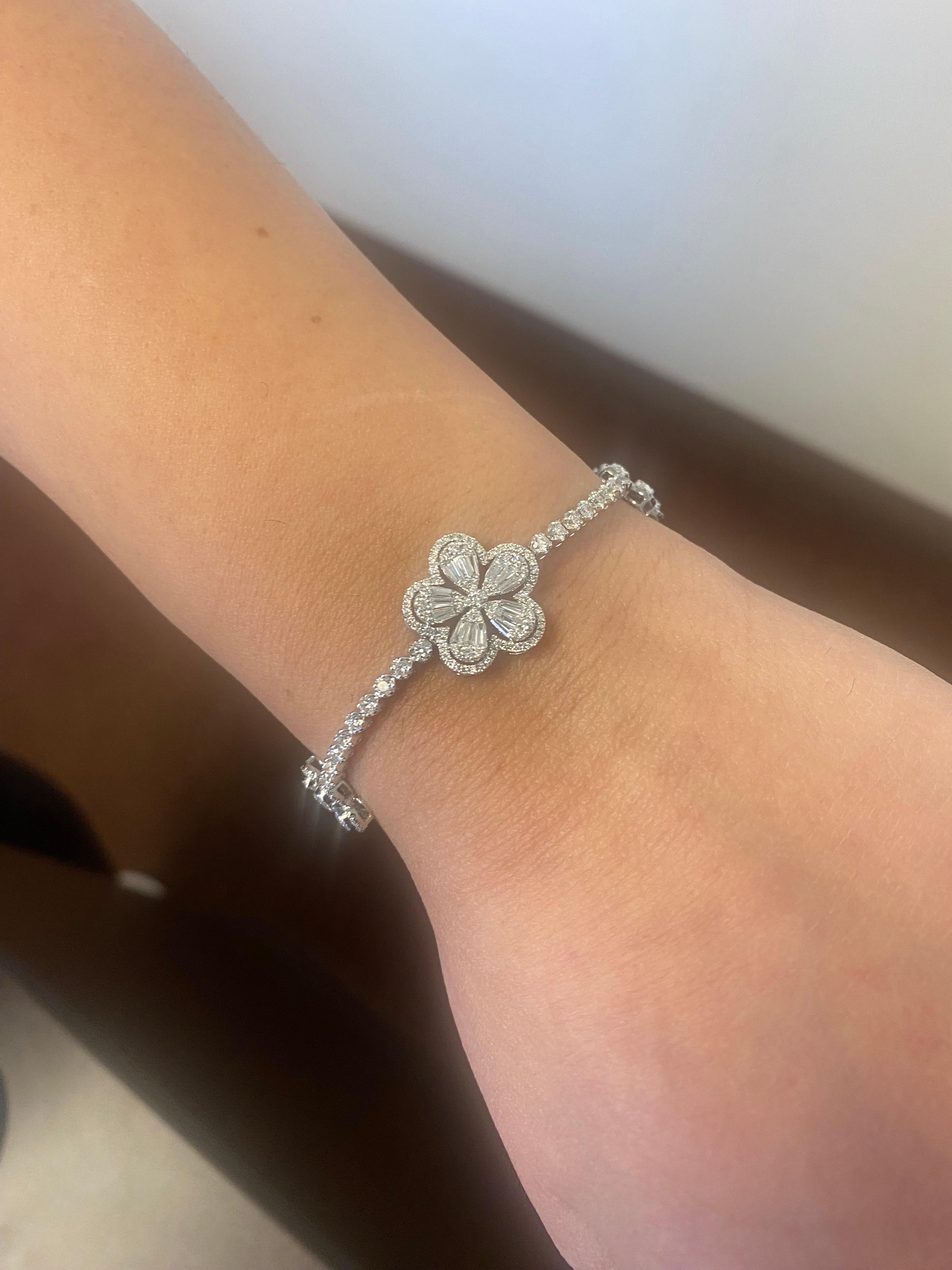 Bracelet de tennis en diamants serti de 4 sections de grappes de fleurs. Le bracelet est serti en or blanc 18 carats. Les fleurs sont serties d'une grappe de diamants baguettes et ronds. Le site  Le poids du diamant est de 3,74 carats. La couleur