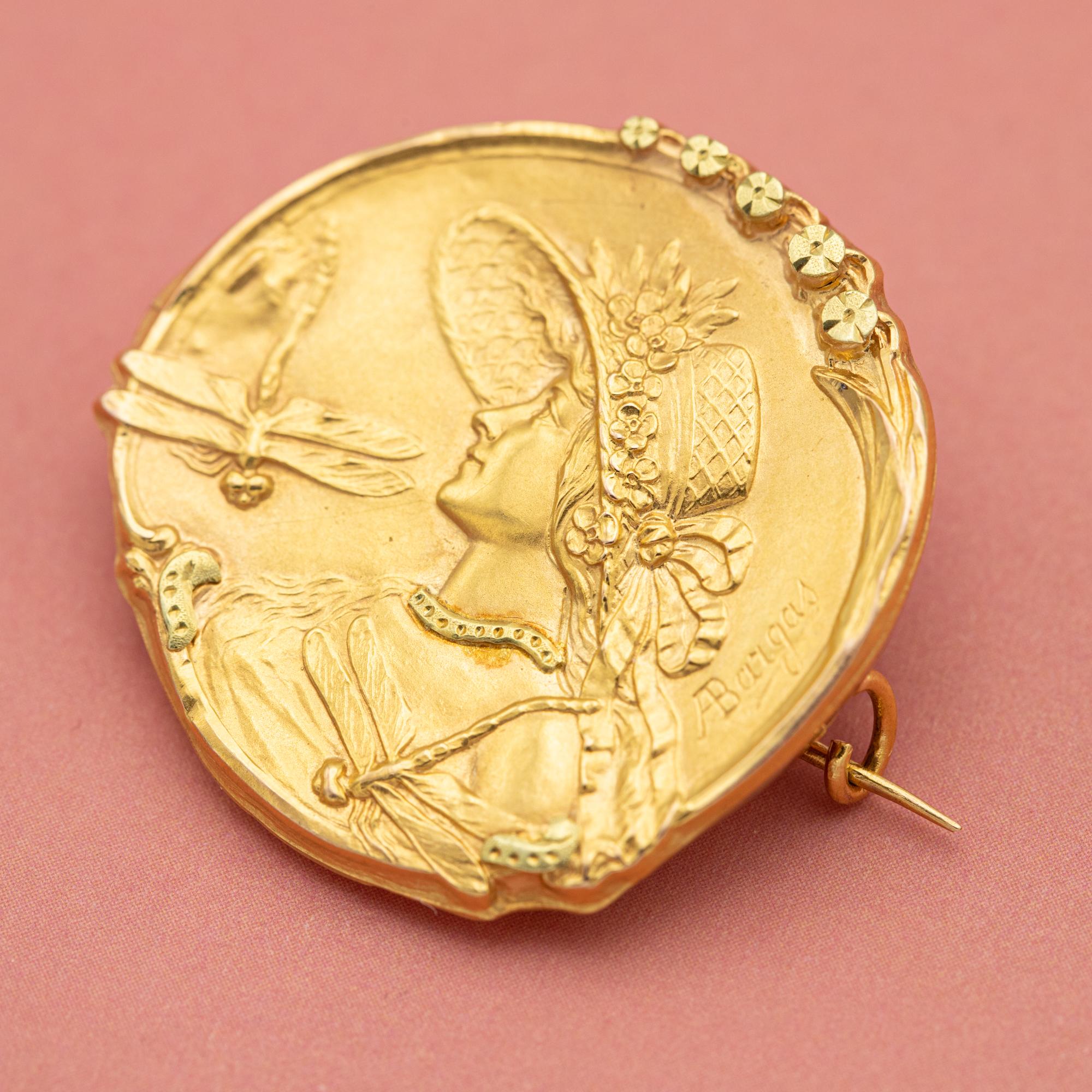 This wonderful bas-relief brooch comes directly from the floral Art Nouveau period. Oval in shape, this lovely antique brooch represents an beautiful woman in profile, her hat adorned with small flowers and her dress made of a drapery. Two elegant