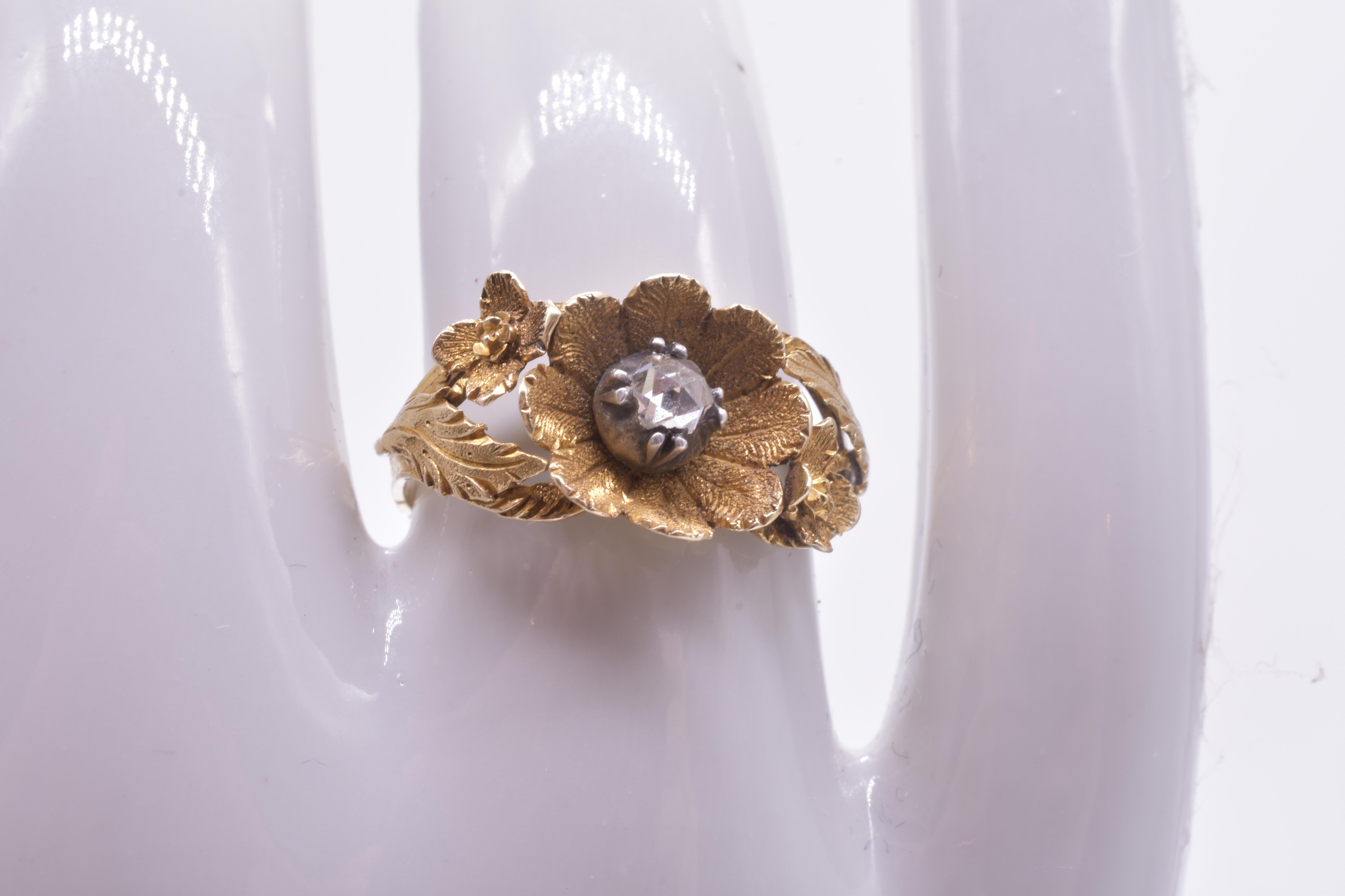 Naturalistically sculpted late Georgian figural flower ring carved in 18K. This ring enchants with its petals and leaves carved in gold and a perfect rose cut diamond set at the center of the flower. The carving of the leaves and petals is lovely,