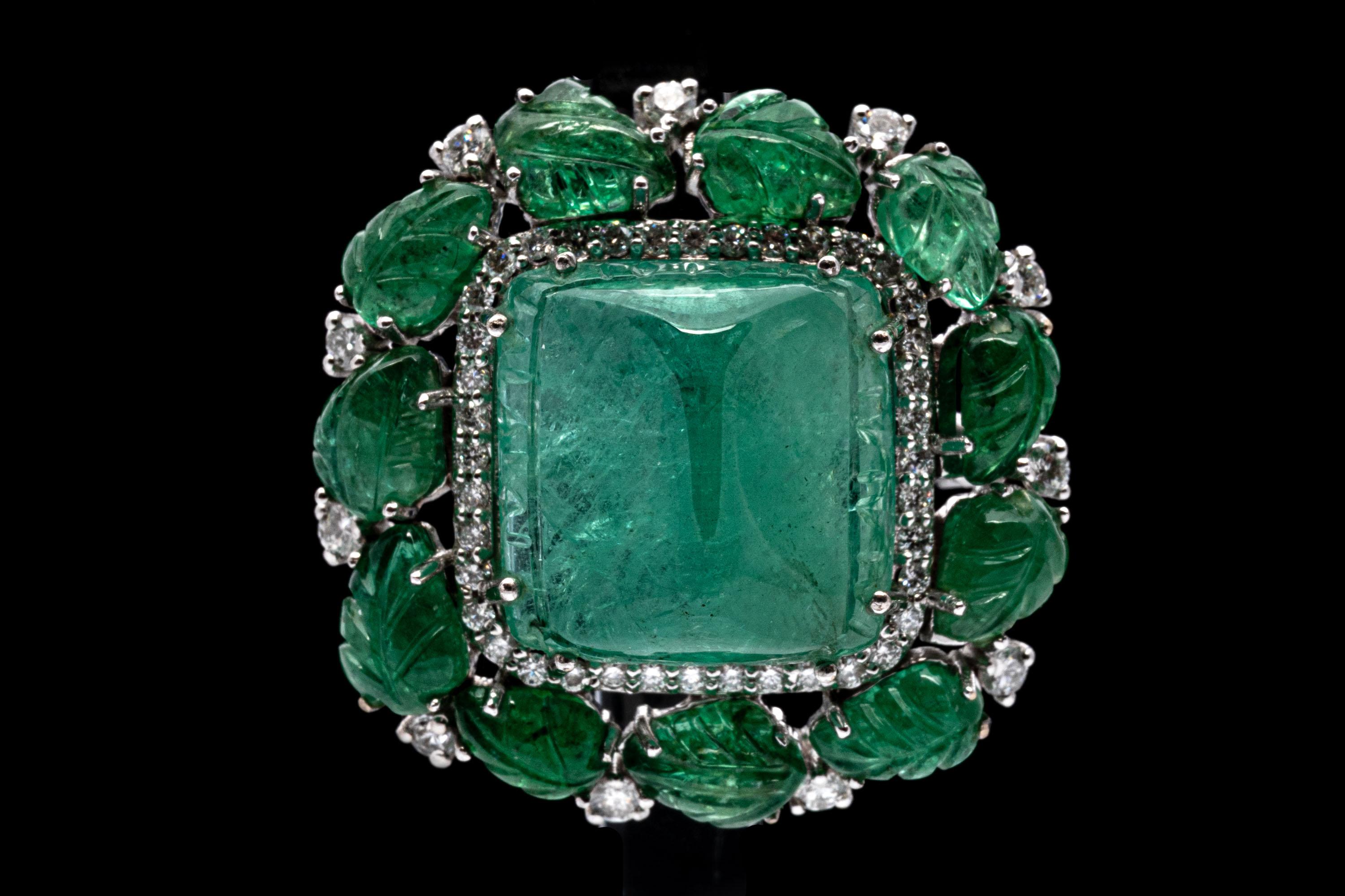 18k white gold ring. This glamorous ring is a wide, cluster style and contains a spectacular, high cabachon sugarloaf cut, medium green color emerald, approximately 15 mm x 15 mm  x 7.75 mm. Surrounding the center emerald is a halo of round faceted