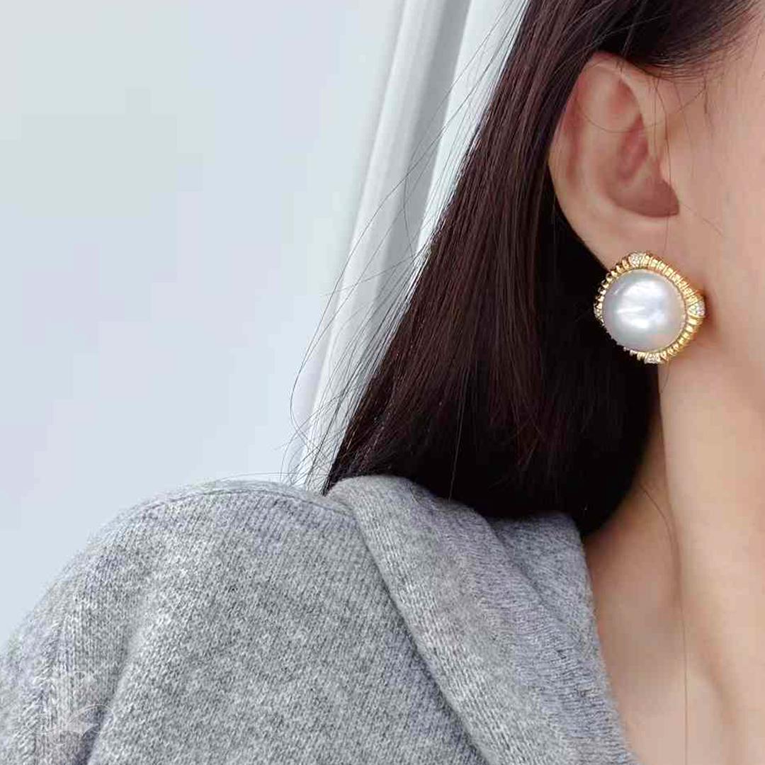 These luxurious earrings feature radiant aurora Mabe pearls certified in Japan, showcasing exceptional luster and beauty. Encased in meticulously crafted heavy gold settings with intricate detailing, each piece measures an impressive 3.2 cm