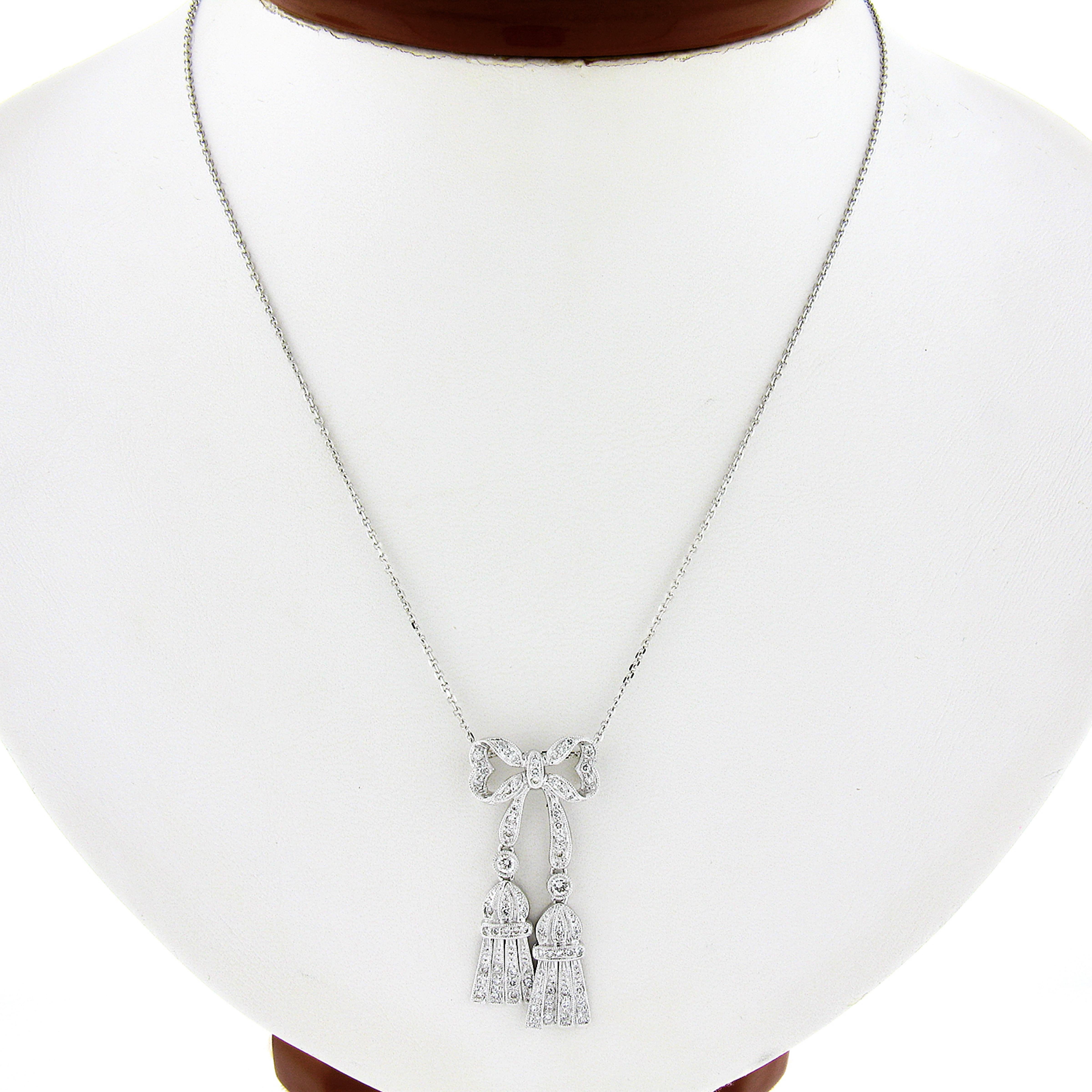 Here we have a beautiful pendant that was crafted in solid 18k white gold and styled as a bow. It features milgrain open work dangle tassels all set with fiery brilliant diamonds! It hangs from a 14k white gold cable link chain that is adjustable to