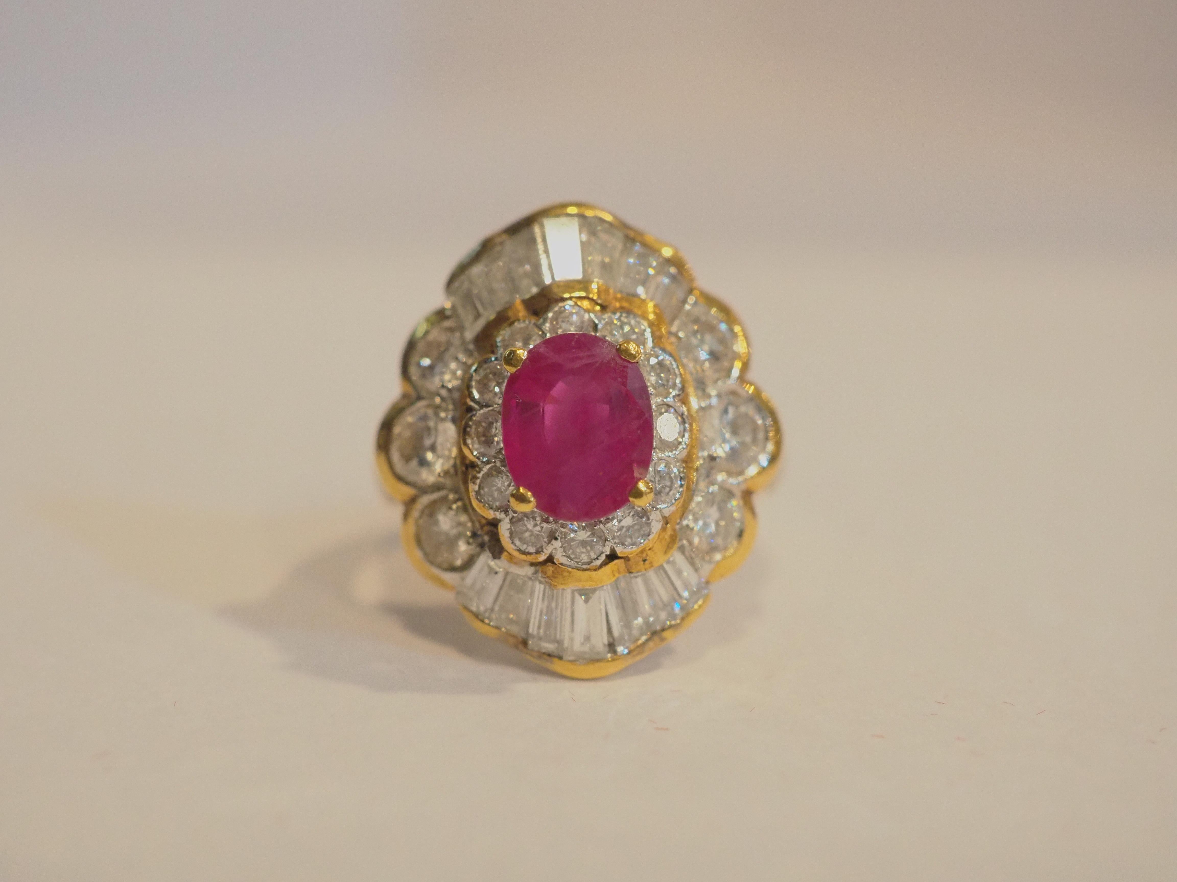 This beautiful and vintage cocktail ring boasts a lovely oval ruby at the center! The ruby is an oval cut and is bright with high saturation of color and with natural inclusions. There are numerous tapered baguette and round diamonds accenting the