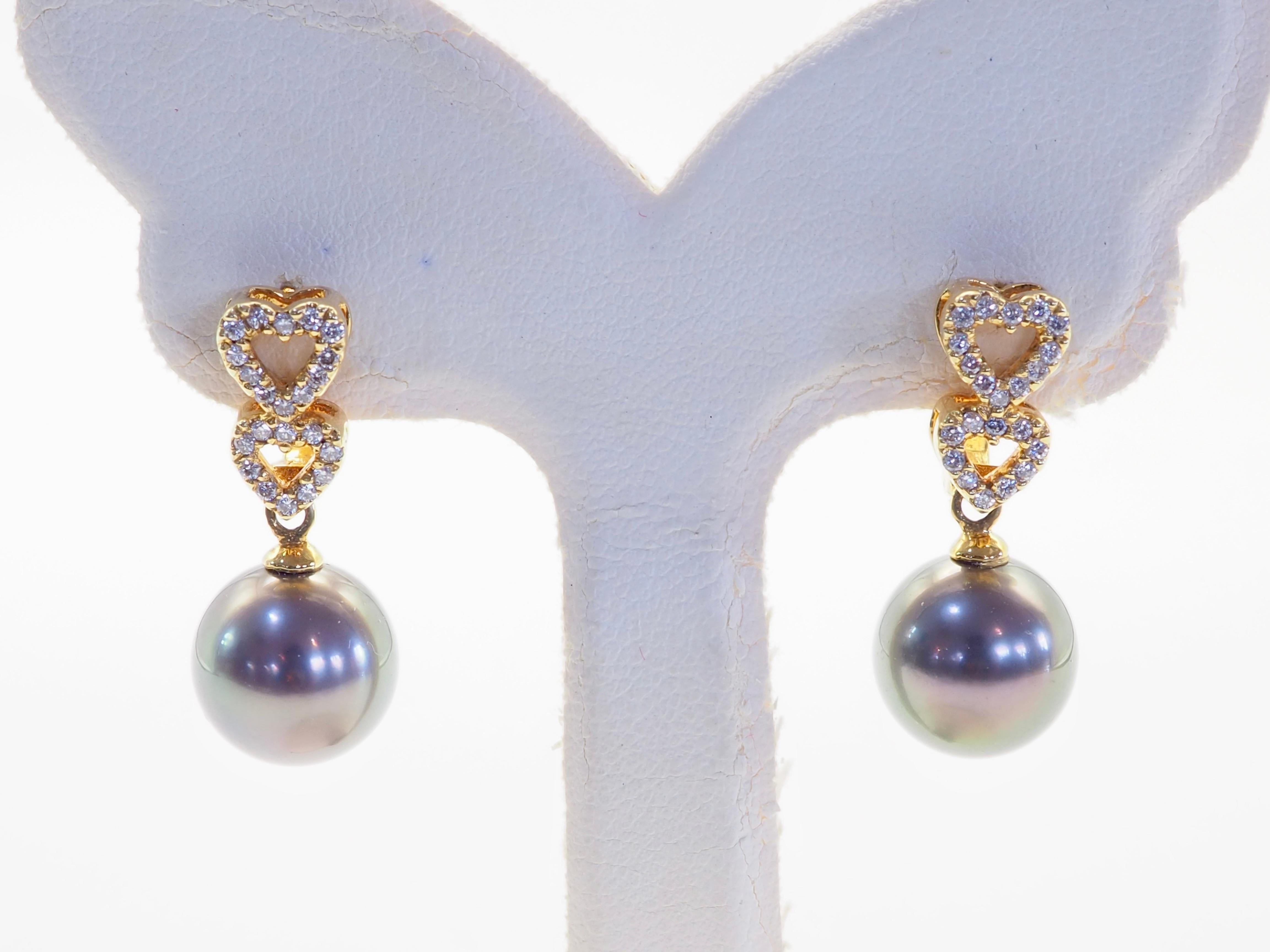 Célébration de l'élégance et de l'émotion, ces boucles d'oreilles pendantes fabriquées à la main présentent un gracieux duo de motifs en forme de cœur en or jaune 18 carats, chacun orné de diamants pavés totalisant environ 0,23 carat. Suspendue en