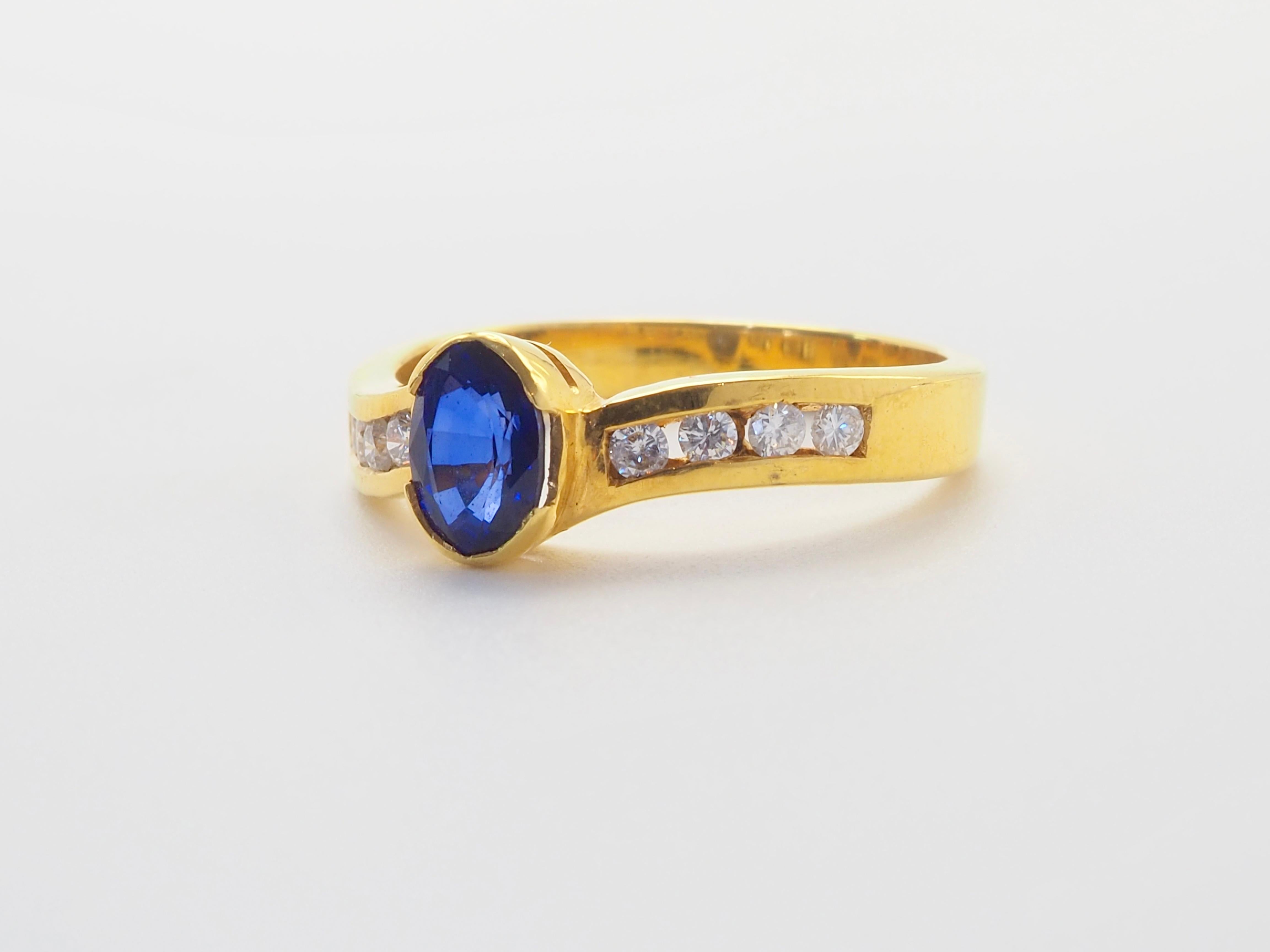 Réalisé en or 18 carats lumineux, cet anneau ondulé sculptural renferme un saphir bleu ovale de 1,10 carat, d'une profondeur et d'un éclat océaniques. Flanquant la pierre centrale, 0,14ct de diamants taille brillant scintillent comme la lumière du