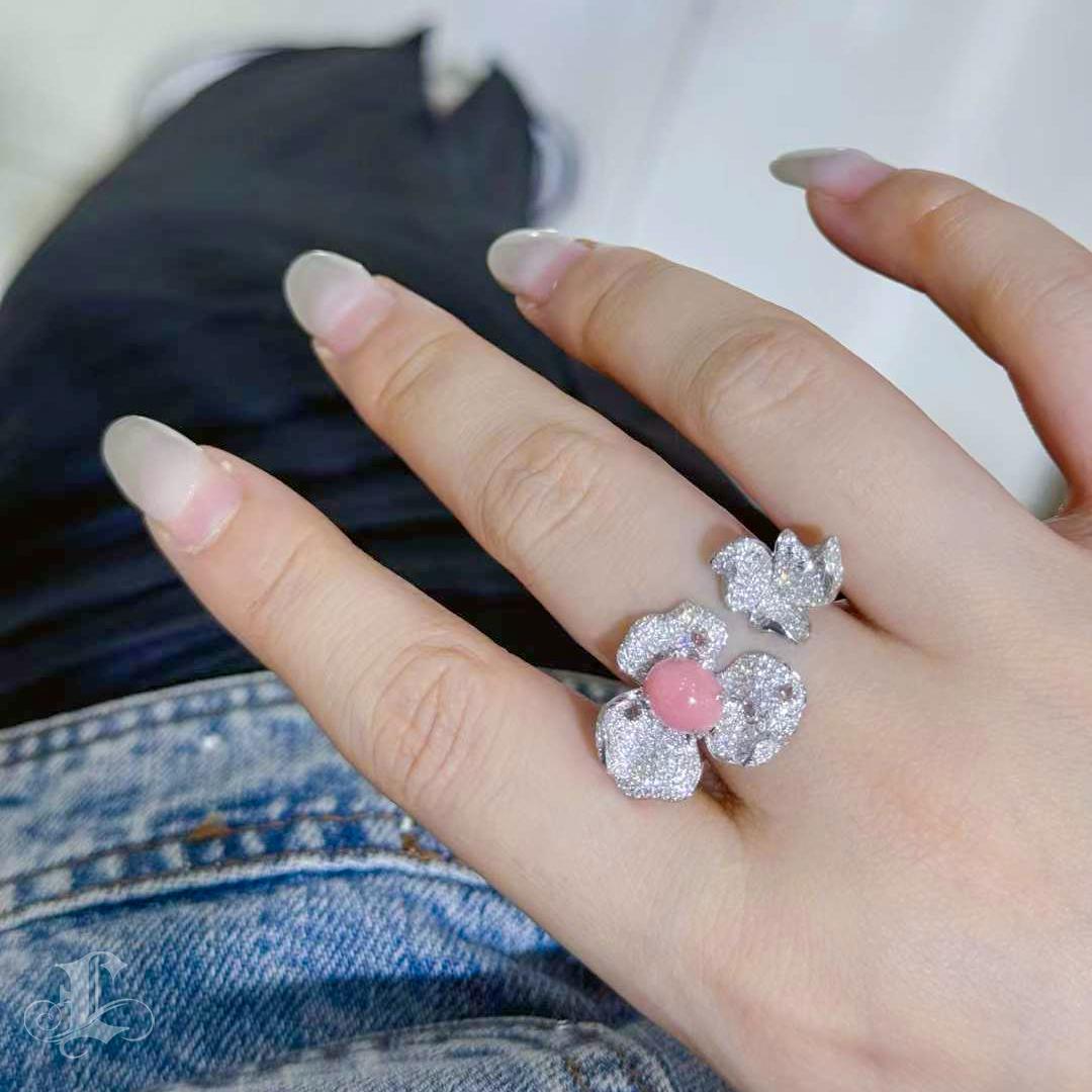 Sculpted with delicate elegance and timeless flair, this flamingo pink conch pearl ring captures the spirit of eternal bloom. The rare pearl—oval in form, with a gentle flame pattern—is cradled by shimmering diamond-pavé petals, evoking a flower at