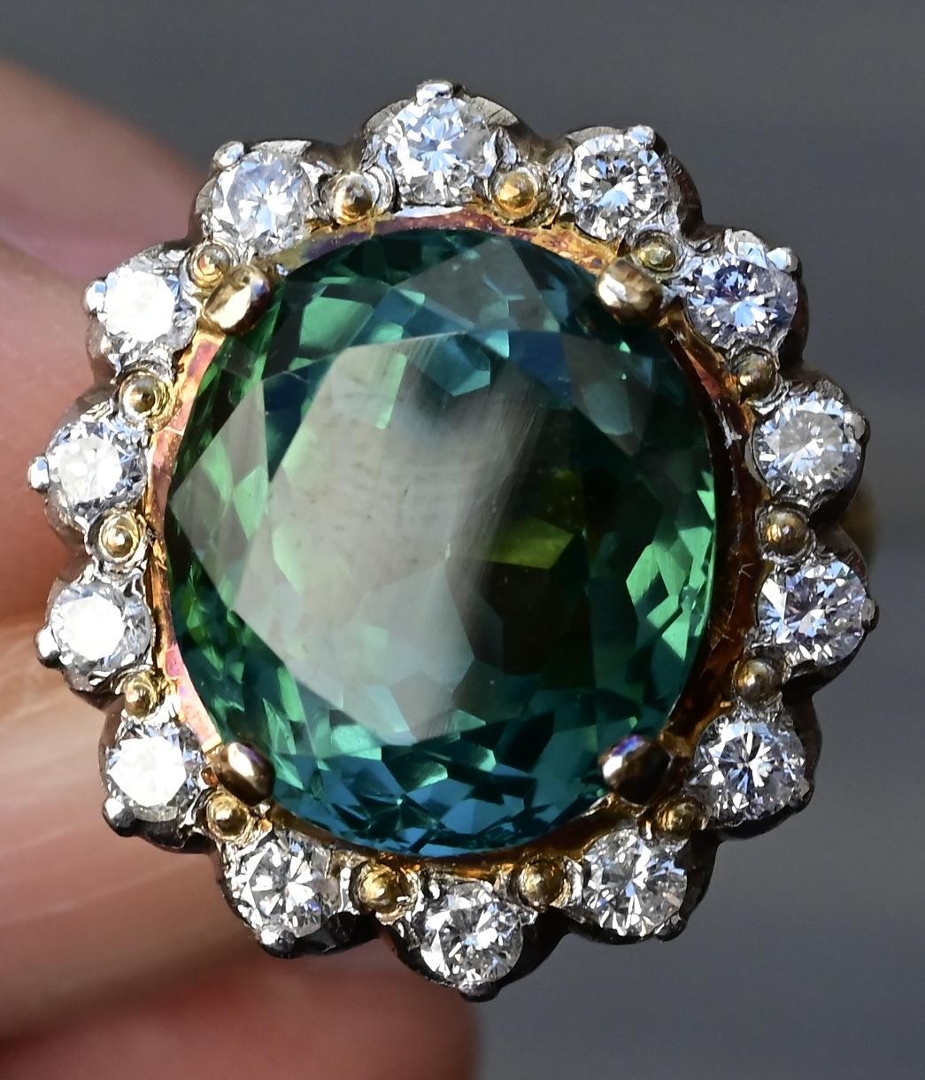 A breathtaking 11.77-carat green tourmaline takes center stage in this stunning 18K gold ring, surrounded by a halo of sparkling diamonds. The diamonds, totaling approximately 0.70-0.75 carats, are graded SI1-SI2 in clarity, offering exceptional