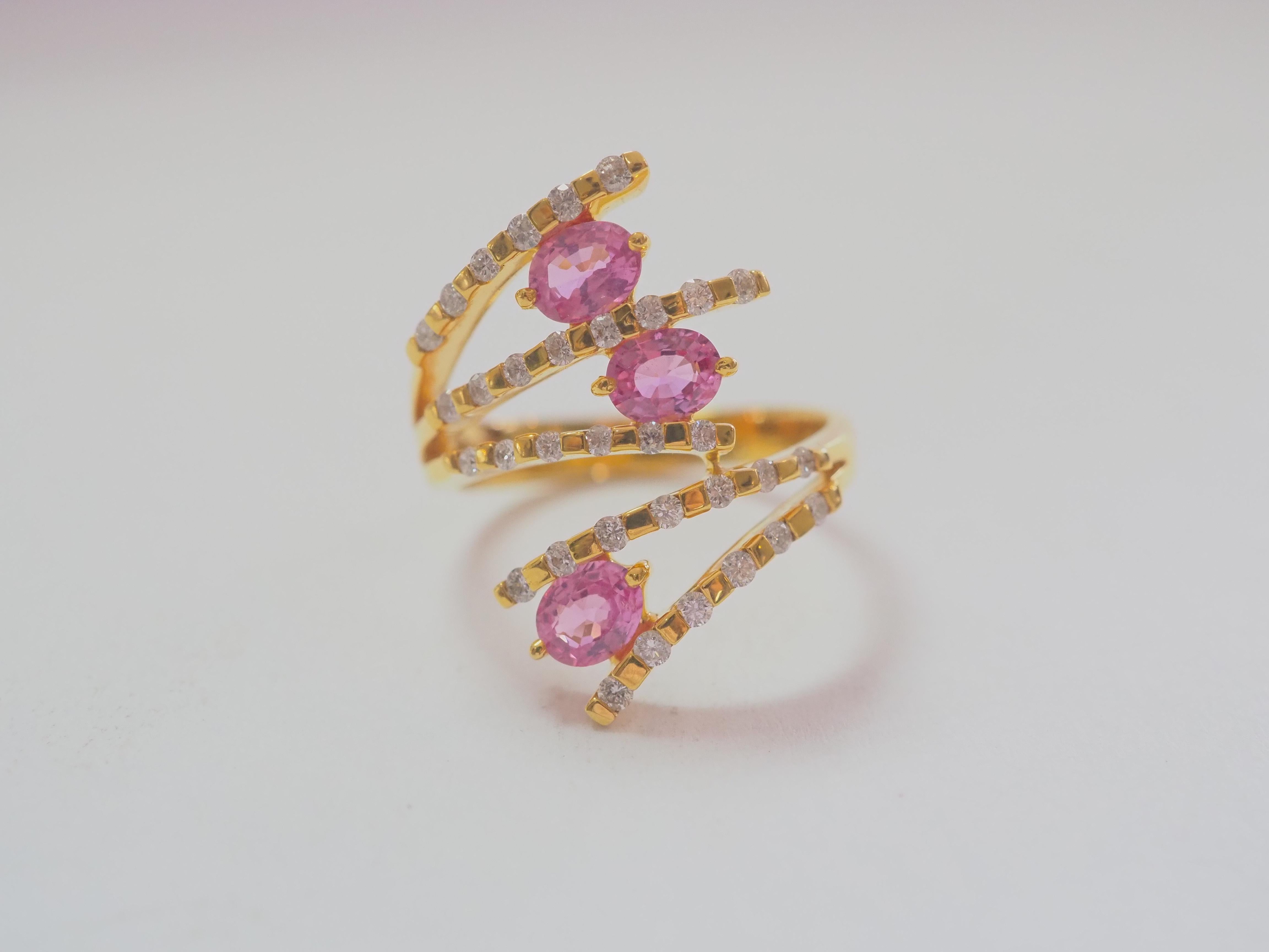 This quality and beautiful wide face cluster ring piece is an 18K solid yellow gold fine quality pink sapphire and diamond ring. 3 hot pink oval pink sapphires are set meticulously and all the same size with matching colors. The round diamonds on