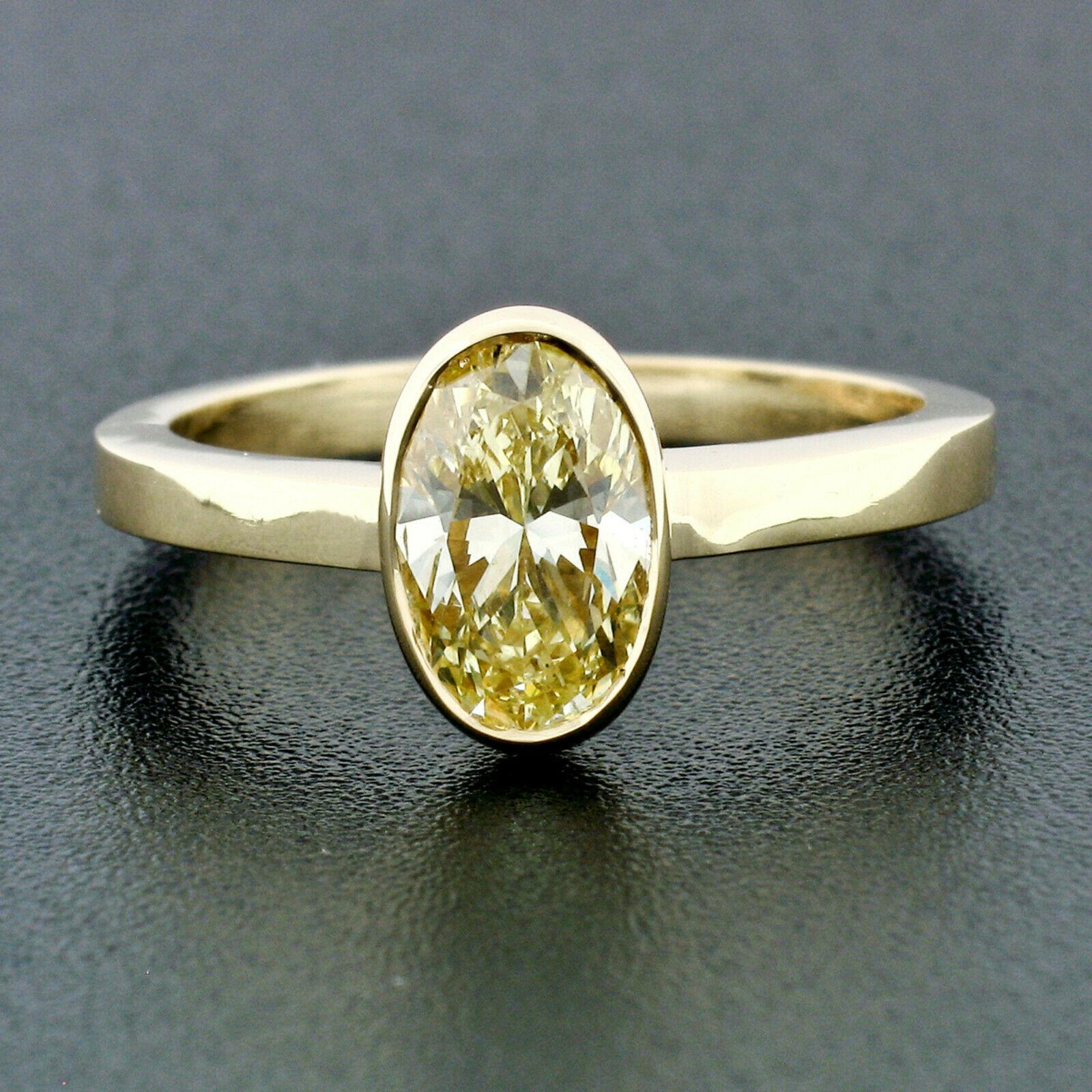 Here we have a simple, yet absolutely gorgeous, colored diamond engagement ring newly crafted from solid 18k yellow gold. The diamond is GIA certified and is a natural, even, fancy yellow color. The solitaire is bezel set at the center of the ring,
