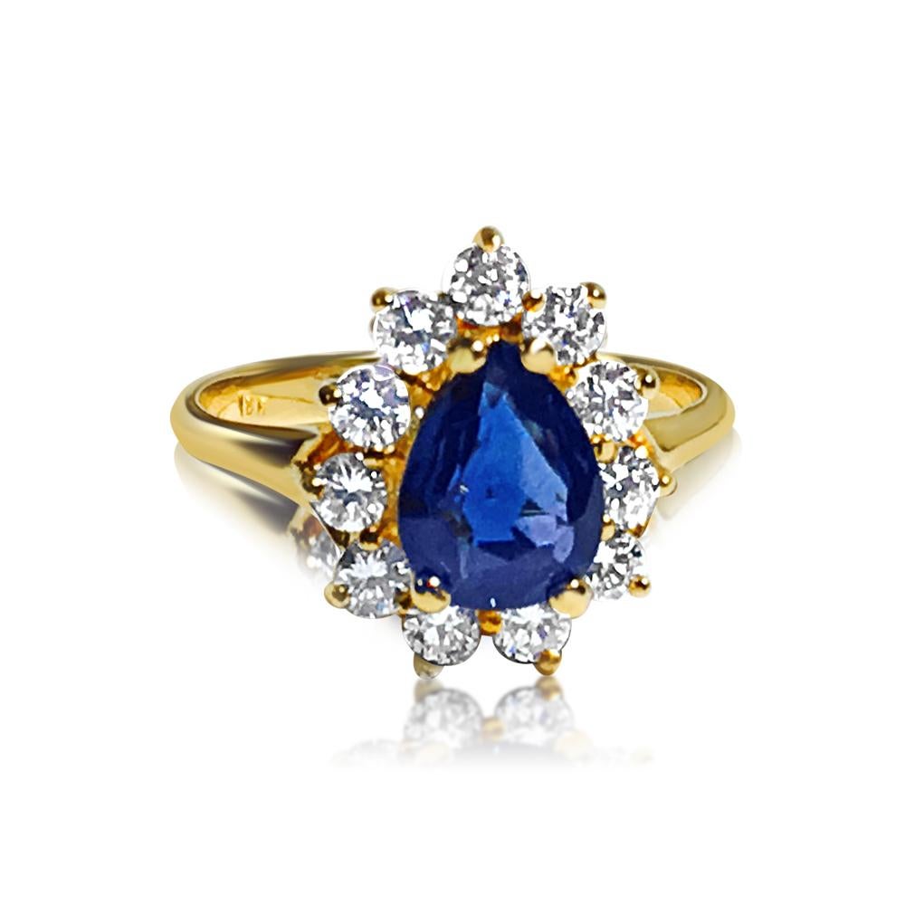 This is a beautiful piece of jewelry made of 18-karat yellow gold. It features a pear-shaped blue sapphire that's 1.50 carats and completely natural. Surrounding the sapphire are round, brilliant-cut diamonds totaling 0.55 carats. All the stones are
