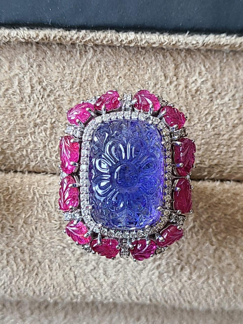 A very wearable and one of a kind, carved Tanzanite & Ruby cocktail Ring set in 18K Gold & Diamonds. The weight of the carved Tanzanite is 21.67 carats and originates from Tanzania. The Tanzanite is completely natural, without any treatment. The