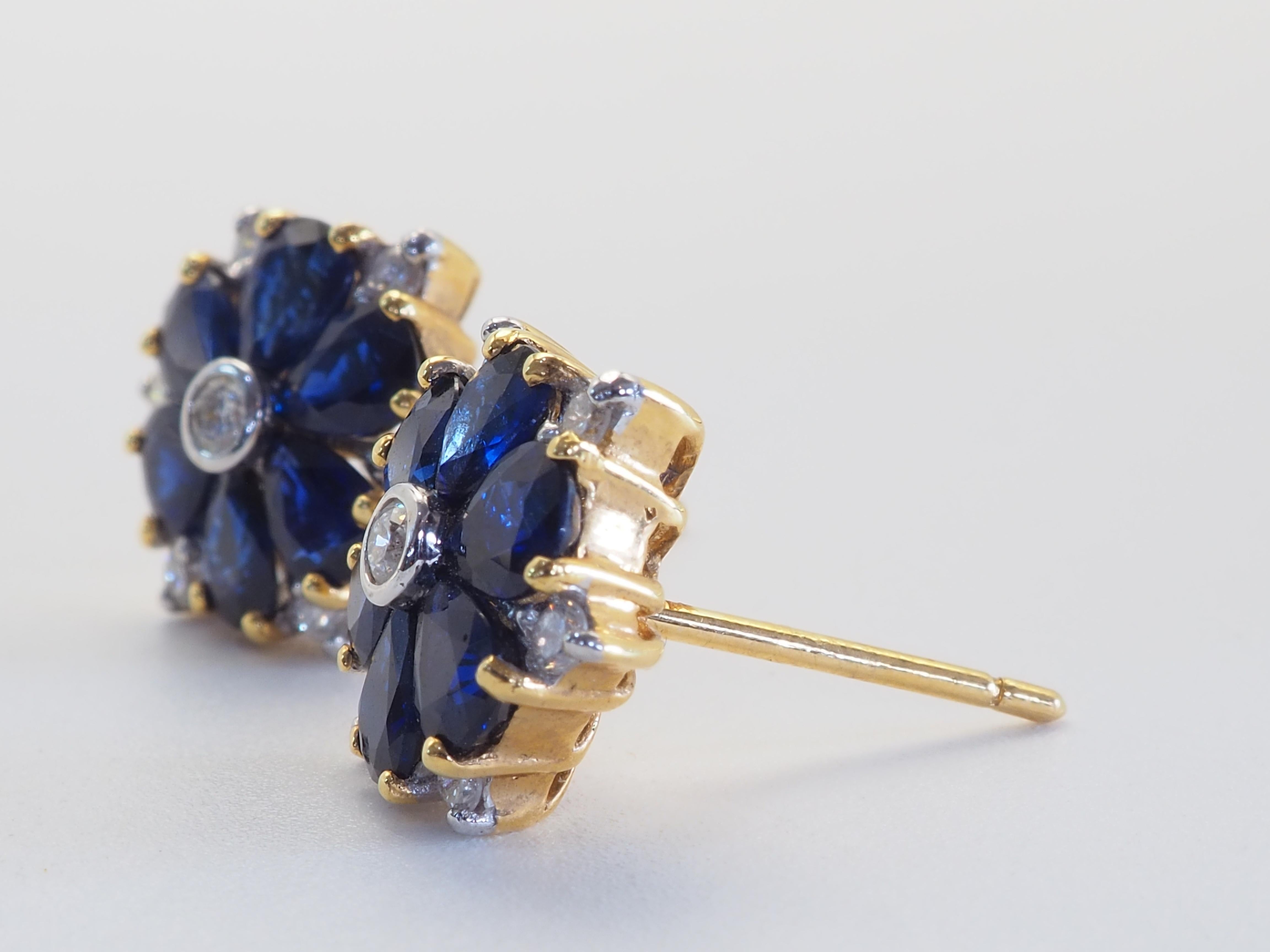 Magnifiques et uniques boucles d'oreilles de style fleuri. Il y a 12 saphirs bleus saturés en forme de poire au total et donc 6 pour chaque oreille. Le décor est impeccable. Les diamants sont vifs et brillants, le bourgeon central étant le plus