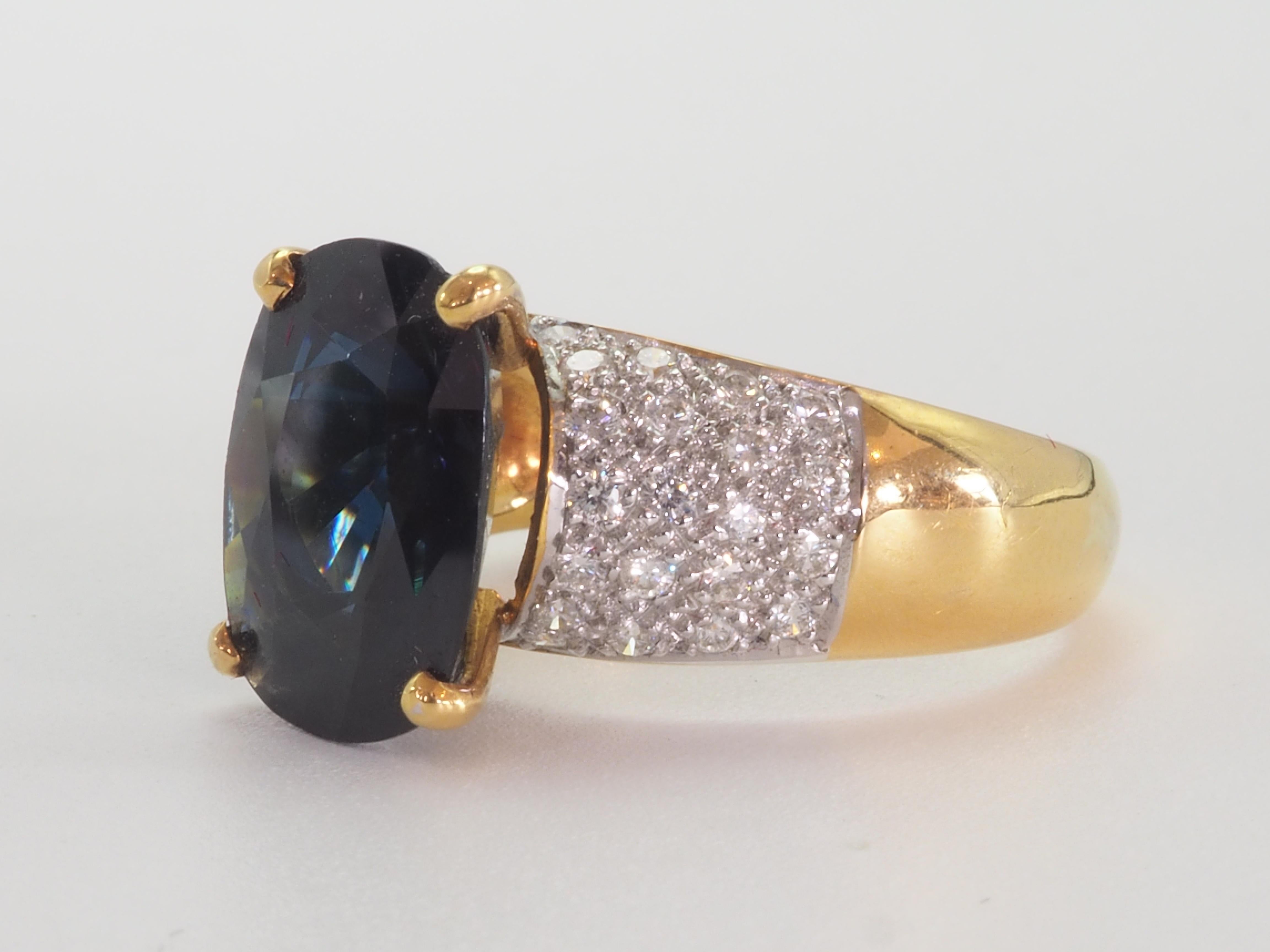 This fantastic vintage statement piece is a beautiful 18K yellow gold ring featuring fine deep greenish- blue sapphire from Thailand. The sapphire is a cushion cut with wide table and is off big size. The color is dark toned, and the surface is