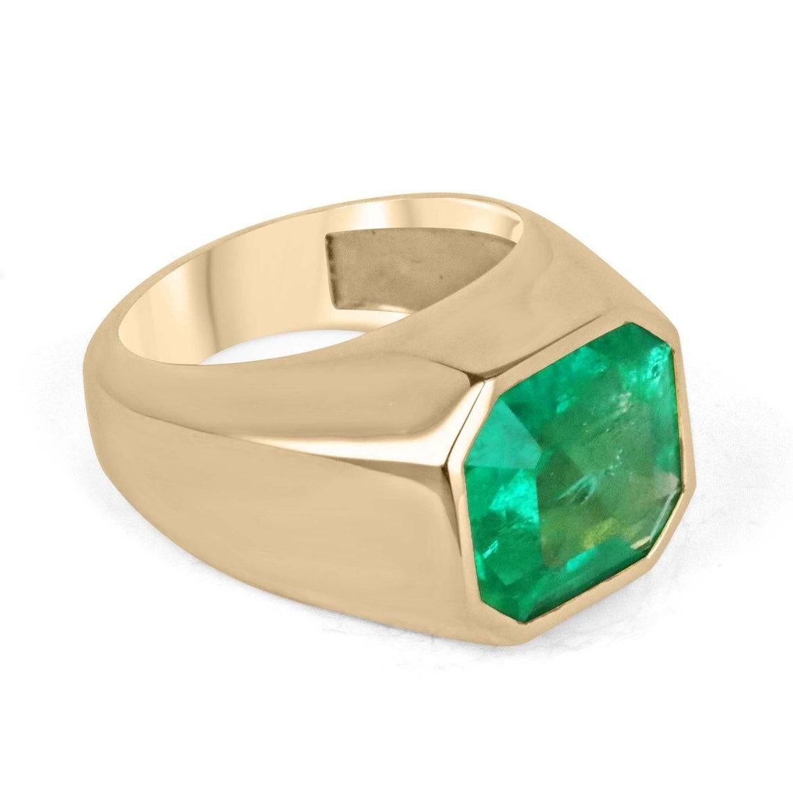 Displayed is a stunning, Colombian emerald signet bezel ring in 18K yellow gold. This gorgeous statement-size solitaire ring carries a 6.55-carat ethically mined emerald in a secure golden bezel setting. Fully faceted, this gemstone showcases a very