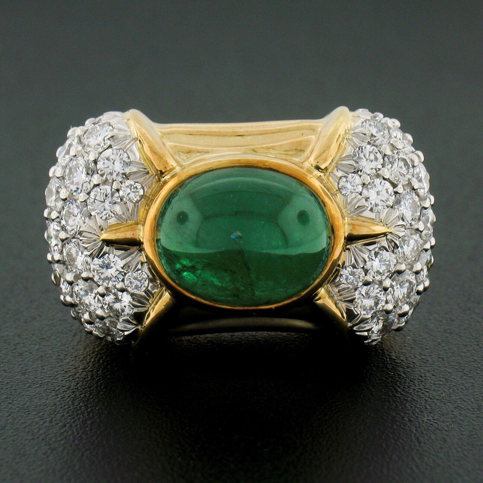 This large, gorgeous cocktail ring was crafted in solid 18k yellow gold and features a magnificent, GIA certified, natural emerald neatly bezel set set at the center of the puffed top. This oval cabochon cut emerald has a fantastic, deep, and vivid