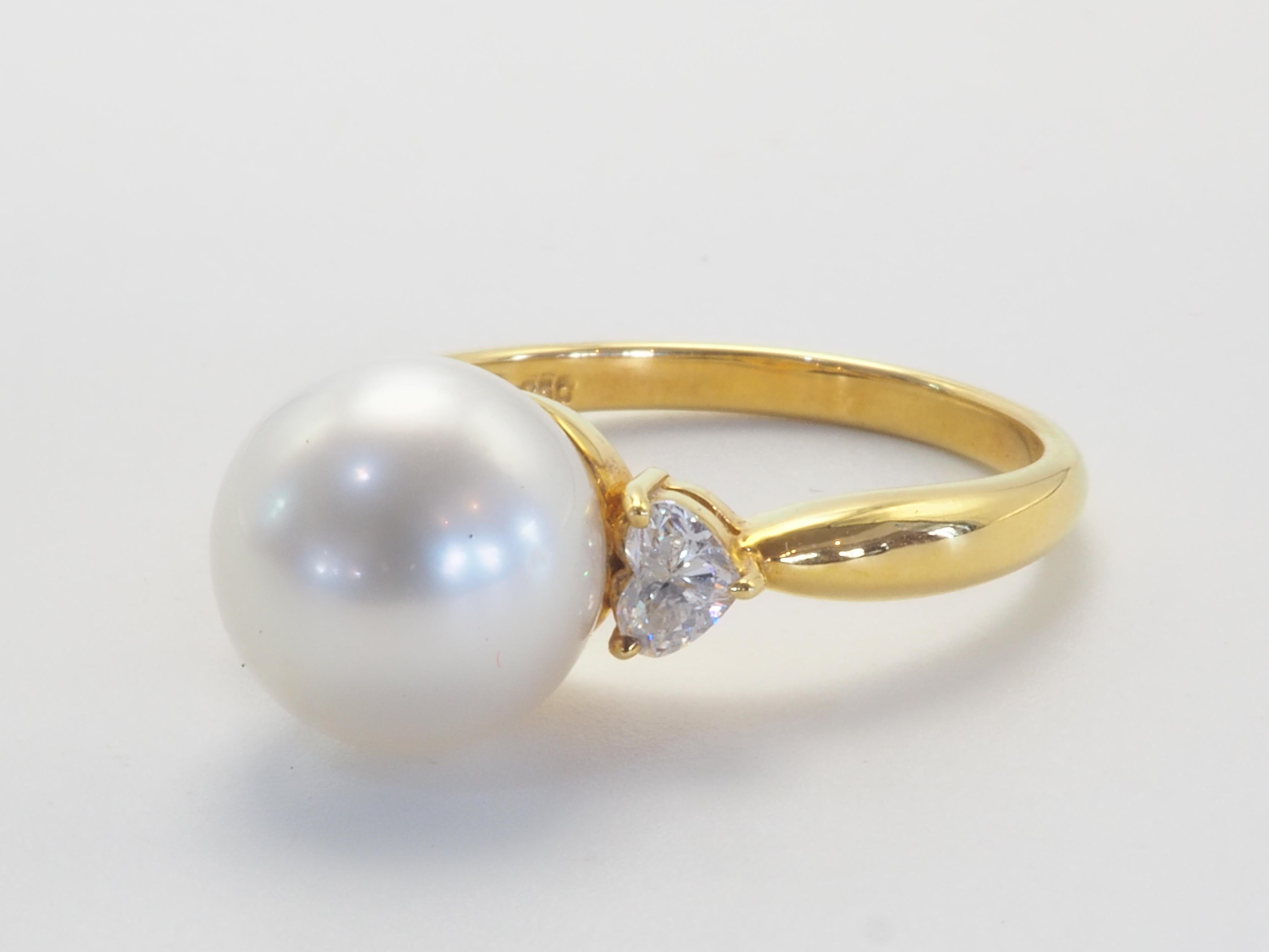 This brilliant 18k gold ring is adorned with a rare and beautiful South Sea pearl! The pearl is perfectly round and has little to no visible blemishes- almost flawless. The diameter of the pearl is around 9.8 mm. The accented heart cut diamonds are